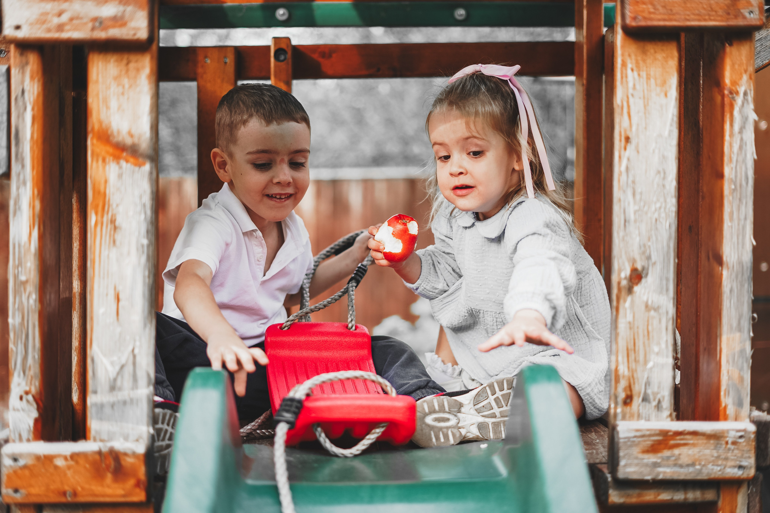 Маленькие брат и сестра играют на горке