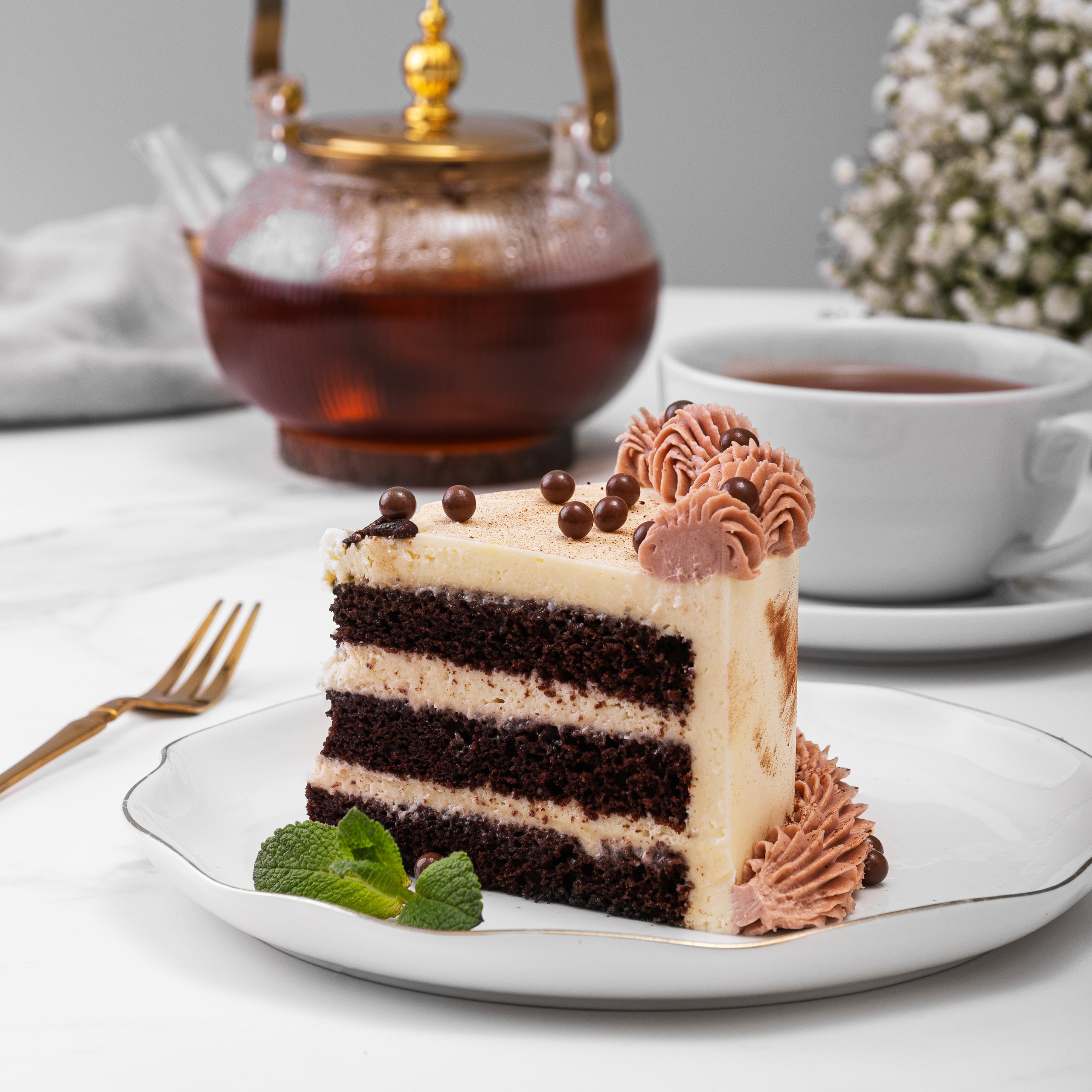 Кусок торта "Прага" на тарелке с чашкой чая 