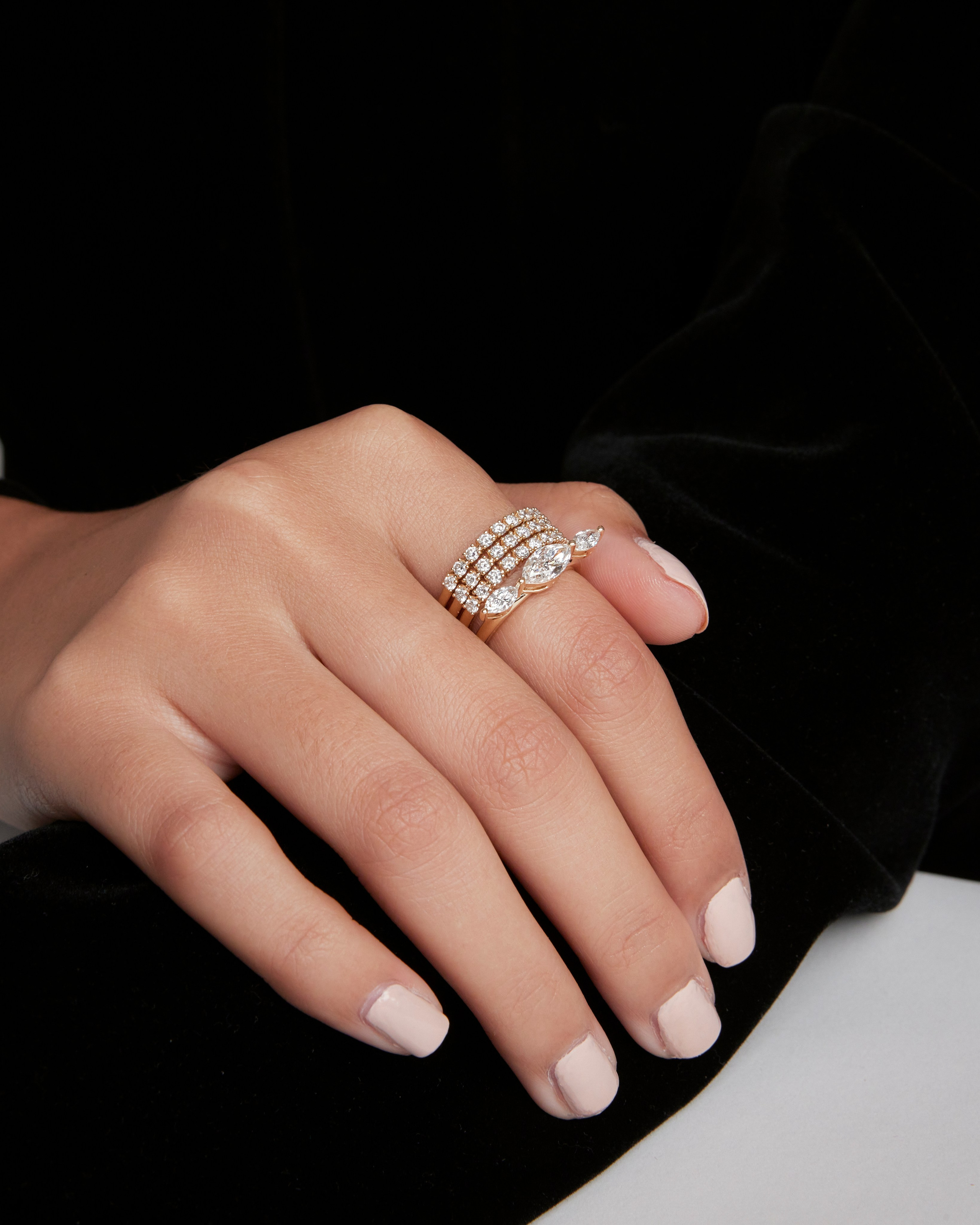 Hands adorned with diamond-encrusted rings against a dark background, emphasizing premium jewelry.