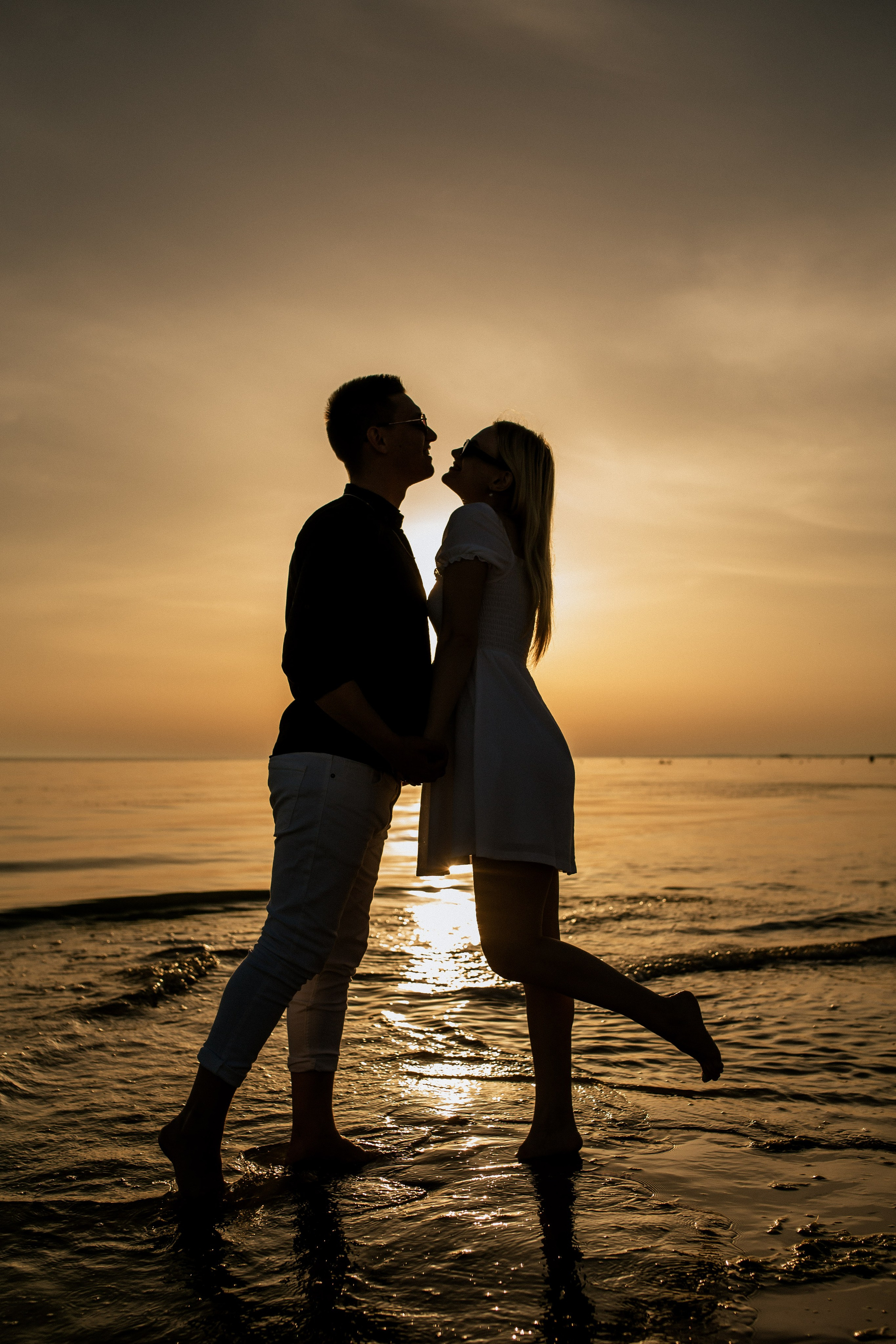 Закатная фотосессия - видны только силуэты влюбленных на фоне закатного солнца.