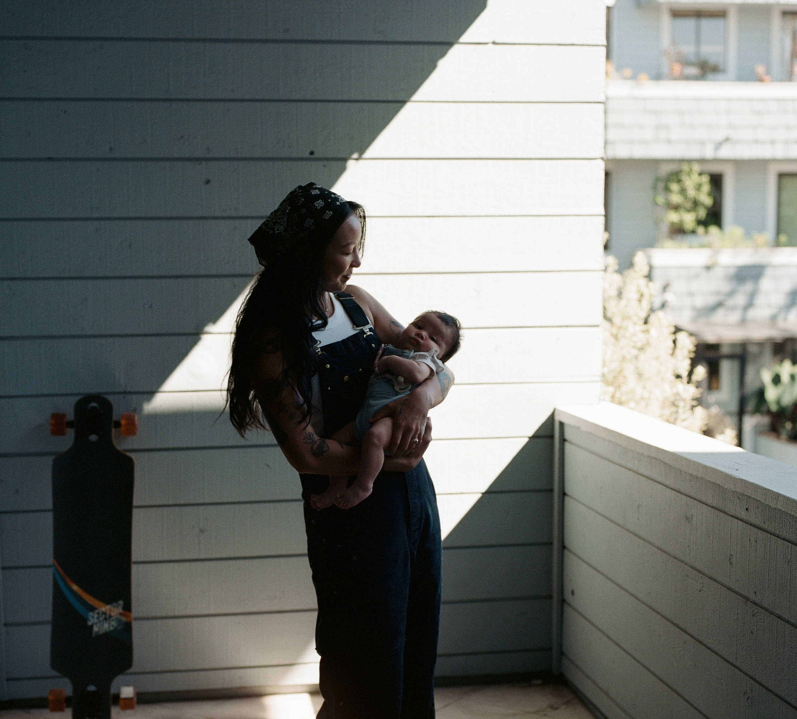 A moment for the baby girl with the mother with long black hair and black overalls on the balcony