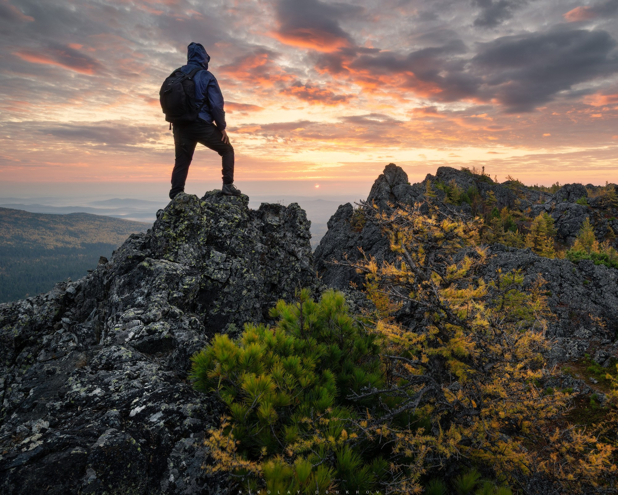 Турист встречает красивый рассвет в горах, на горе Серебрянский Камень в окрестностях горы Конжаковский Камень.