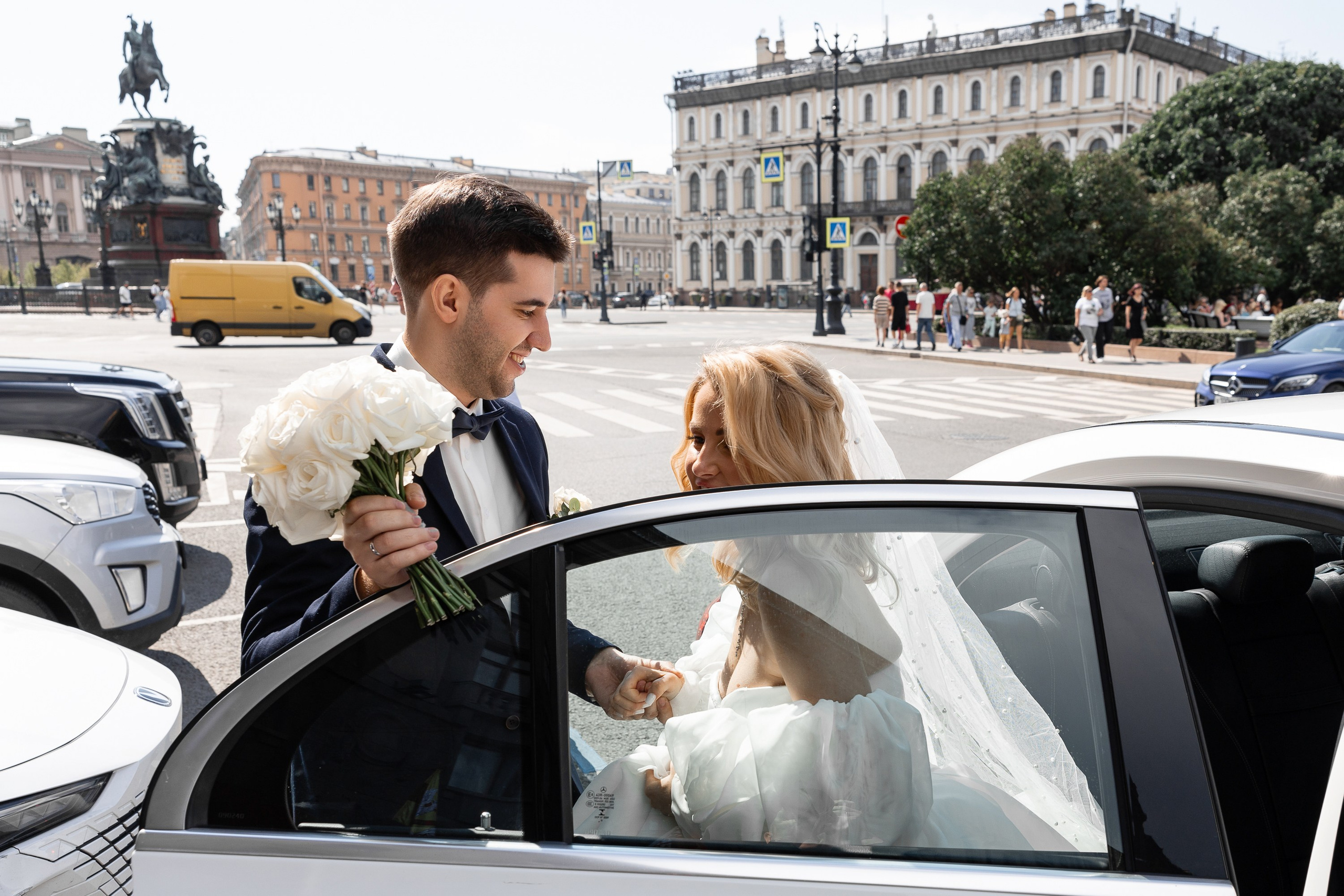 Жених помогает невесте выйти из машины для фотосессии на Исаакиевской площади