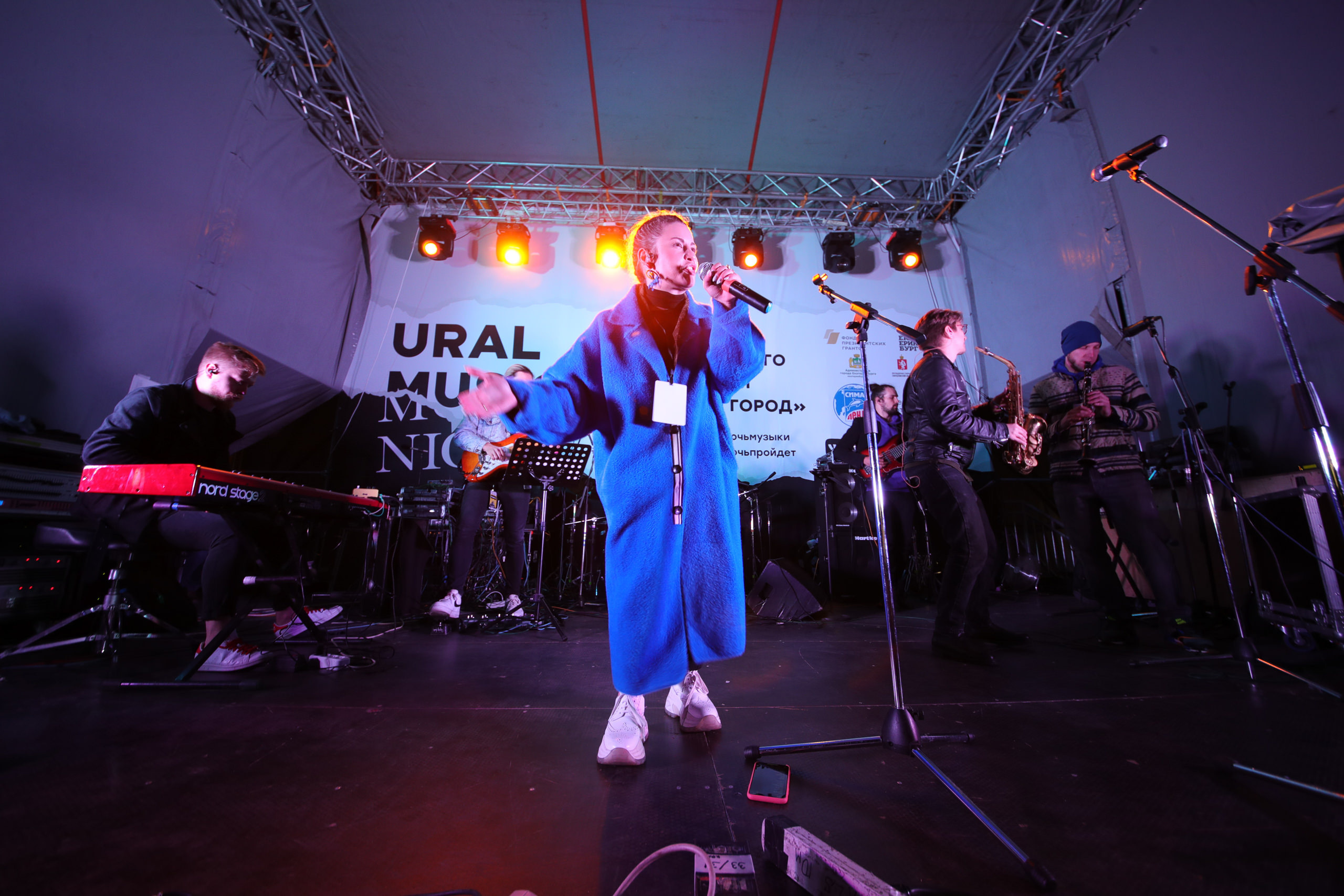 девушка поёт на сцене в синем пальто