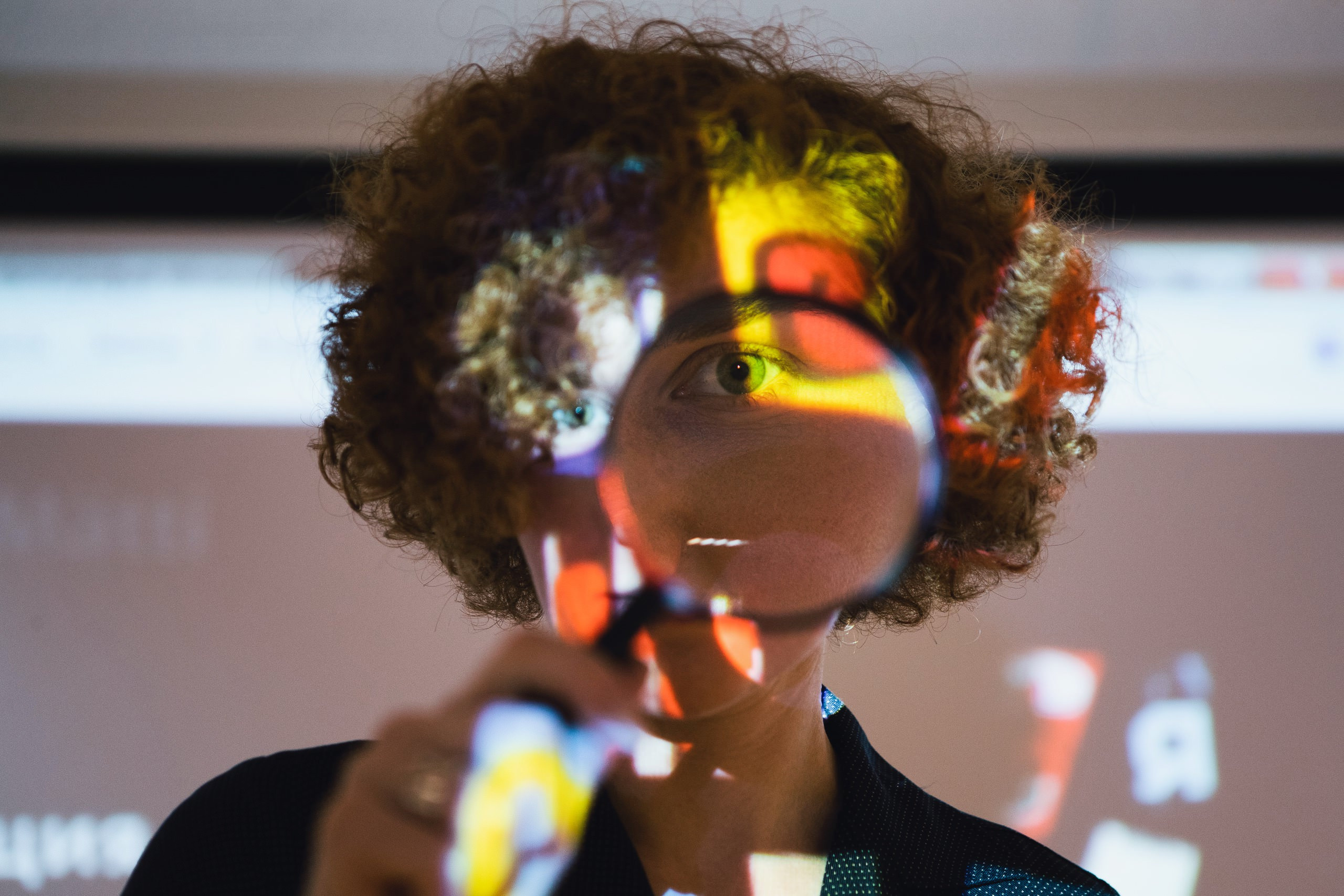 девушка смотрит через увеличительное стекло лупы, большой глаз