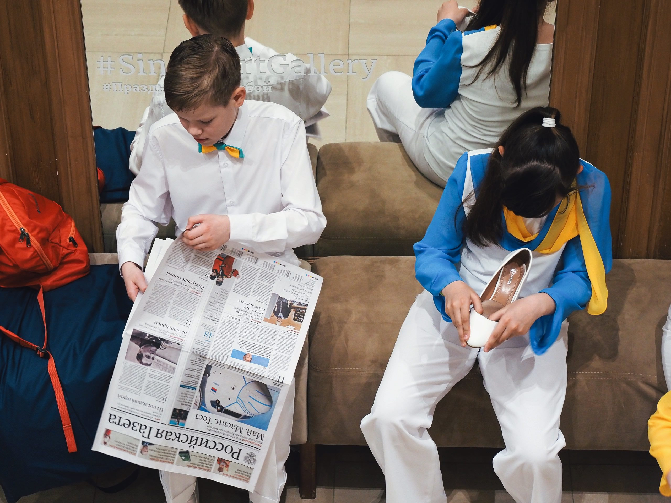 мальчик читает российскую газету, а девочка рассматривает туфлю