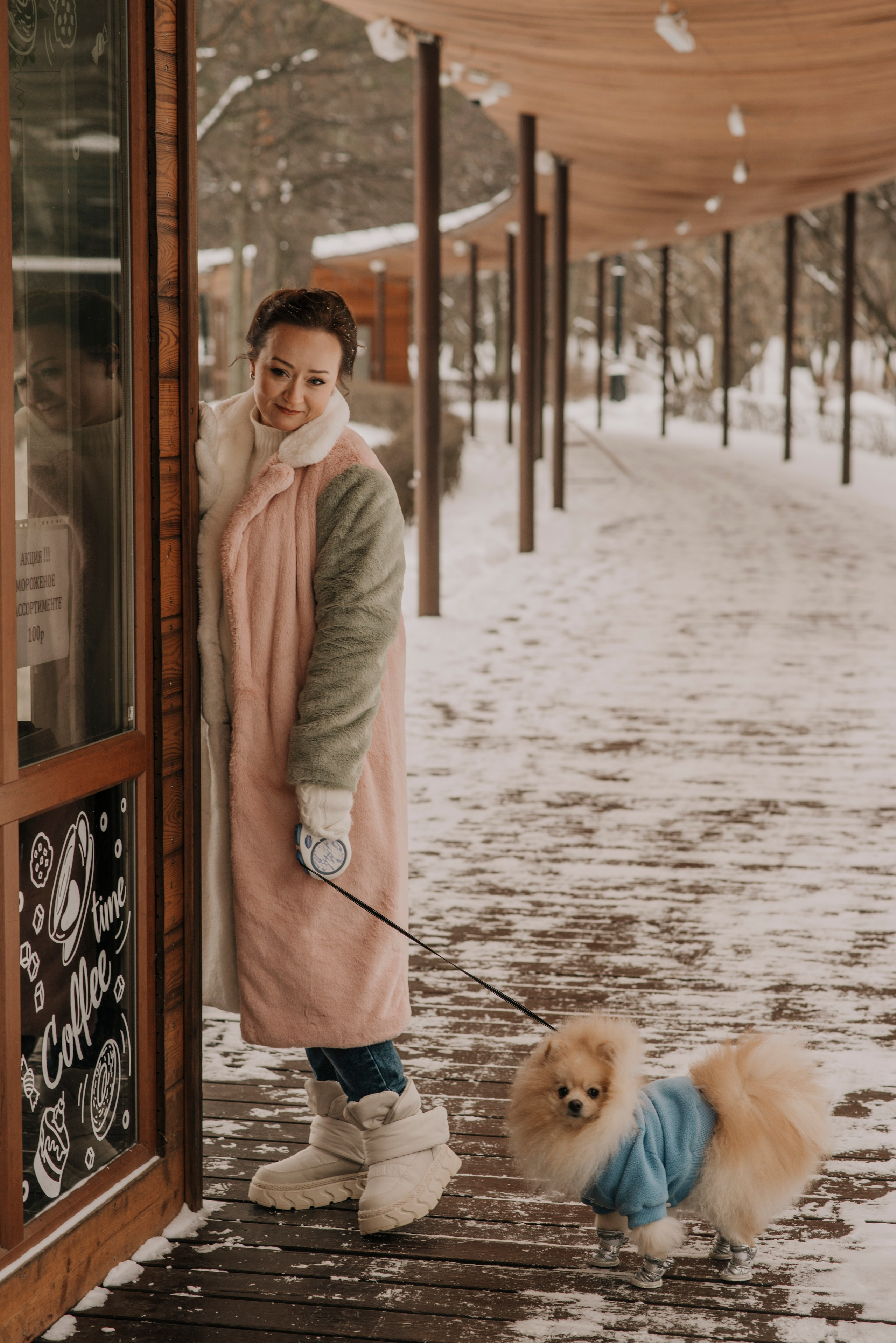 Зимняя фотосессия на фоне закрытого кафе в заснеженном парке с собакой шпицем