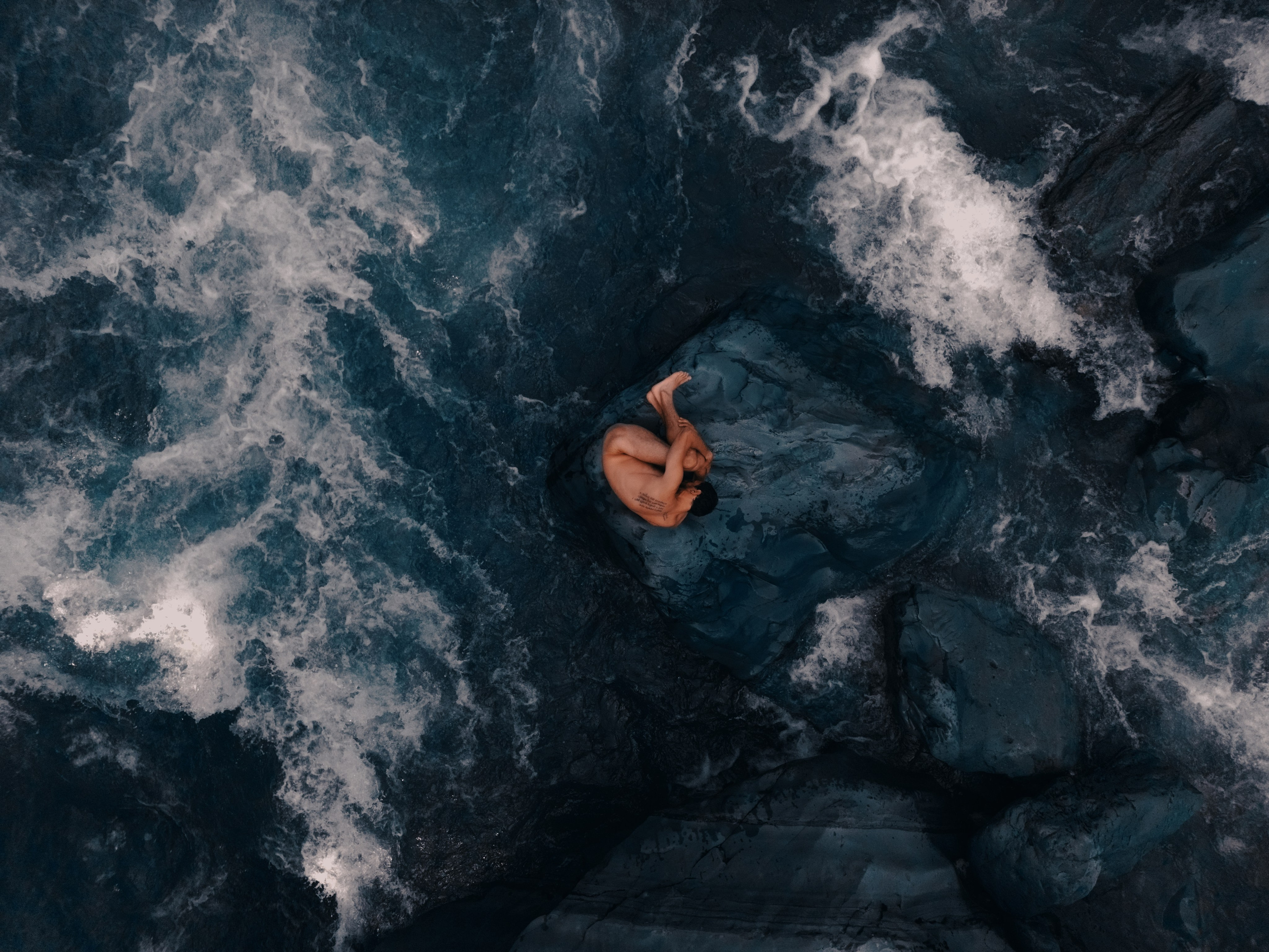 Съемка парня сверху с коптера на фоне реки и камней 