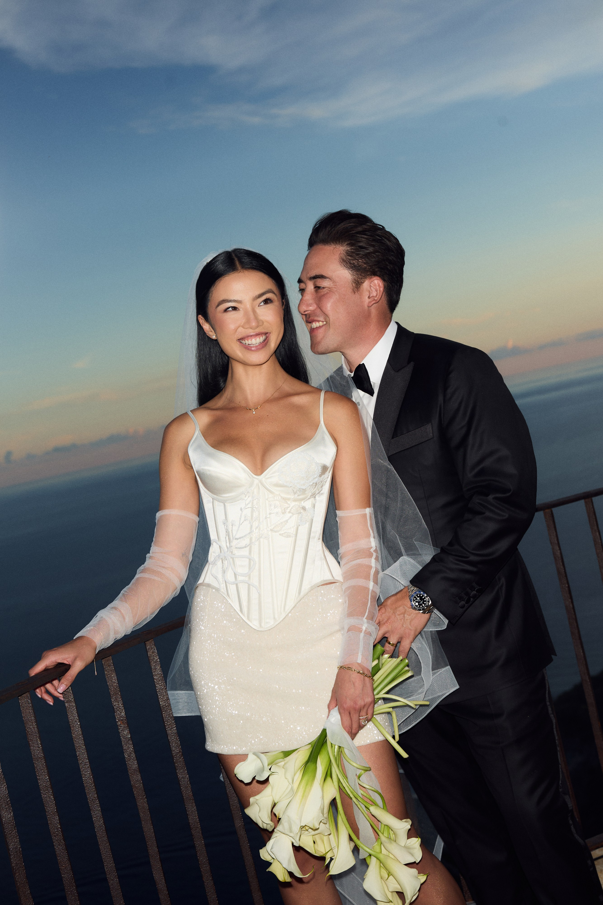 Bride and groom smiling together with the Amalfi Coast behind them
