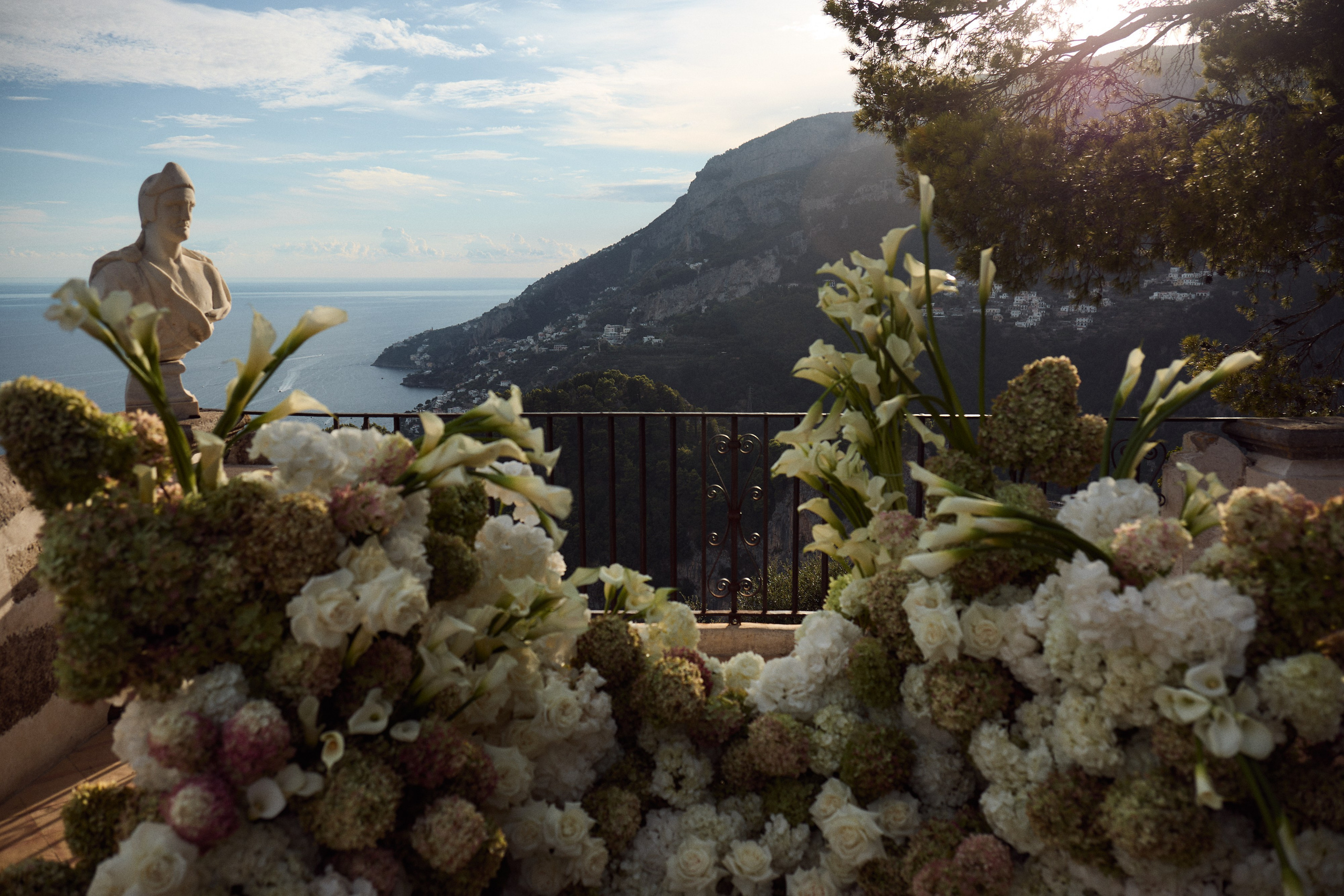 Ceremony flowers beside a marble bust overlooking the Amalfi Coast