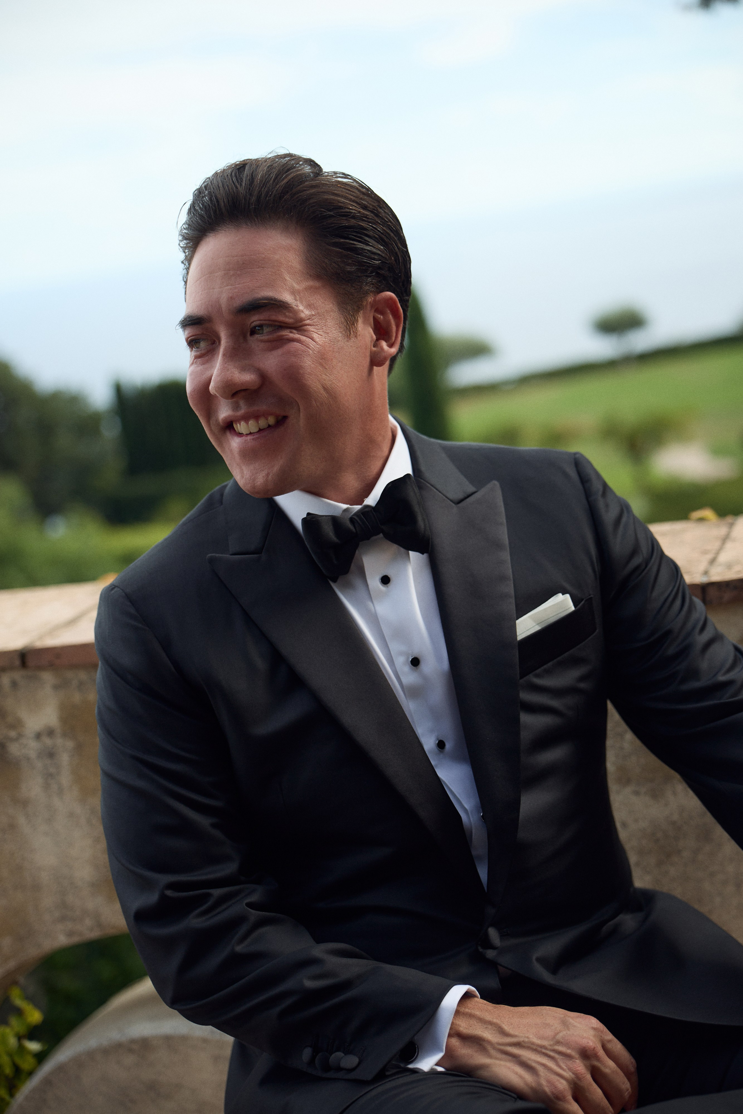 Close-up of the groom smiling in a black tuxedo