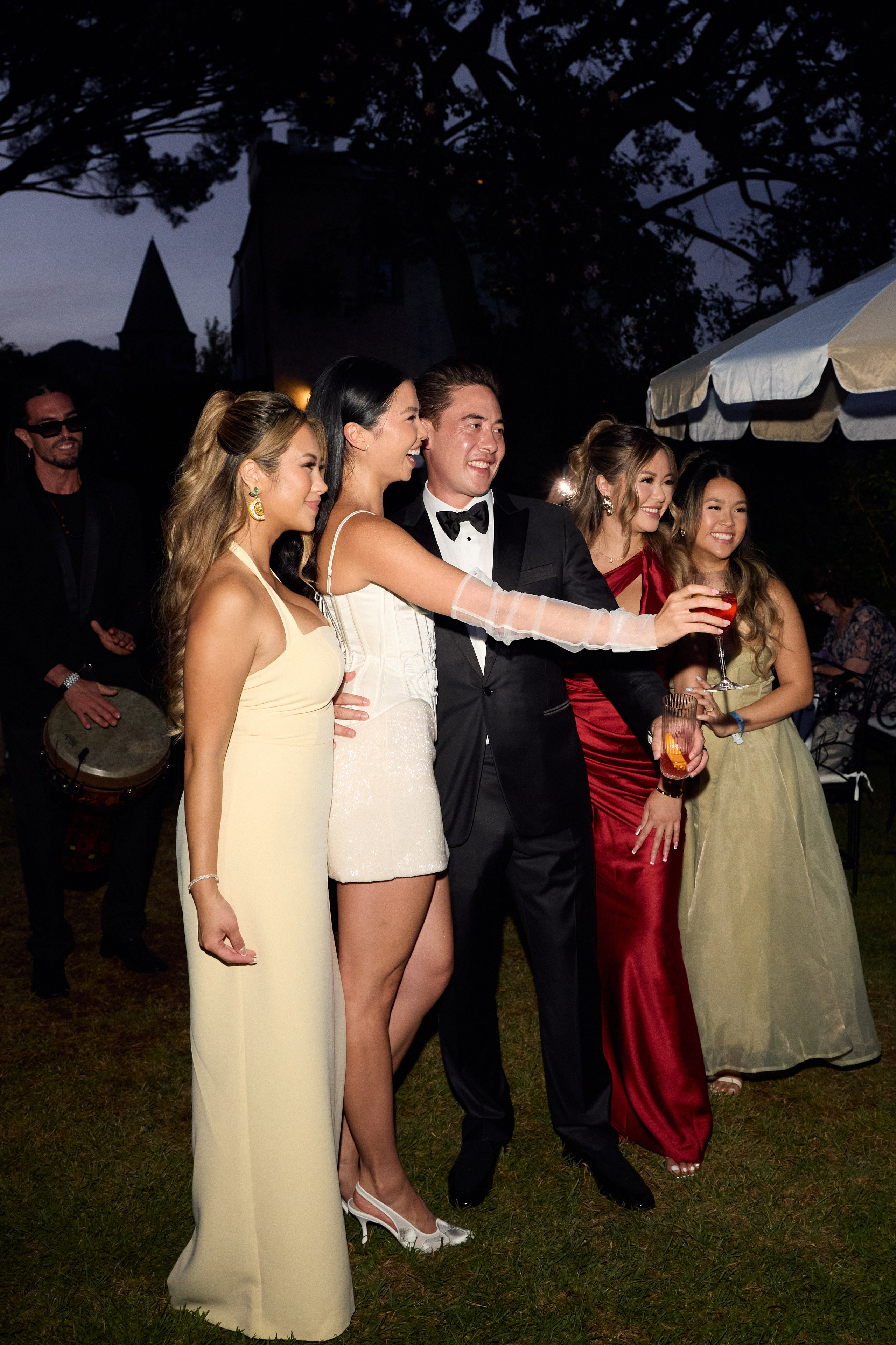 Bride raising a glass with the groom and guests in the gardens