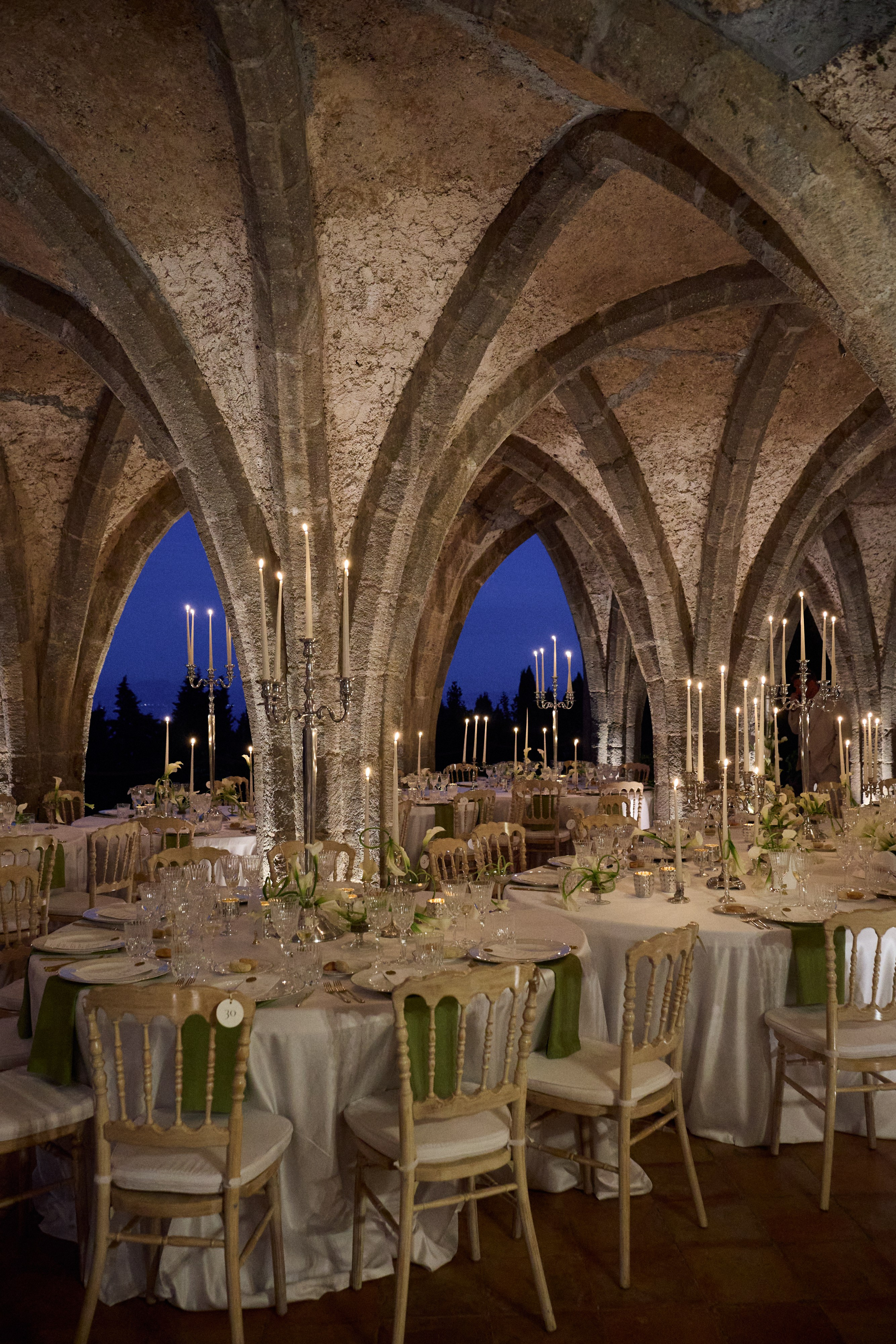 Wedding tables with tall candles beneath the stone vaults of Villa Cimbrone