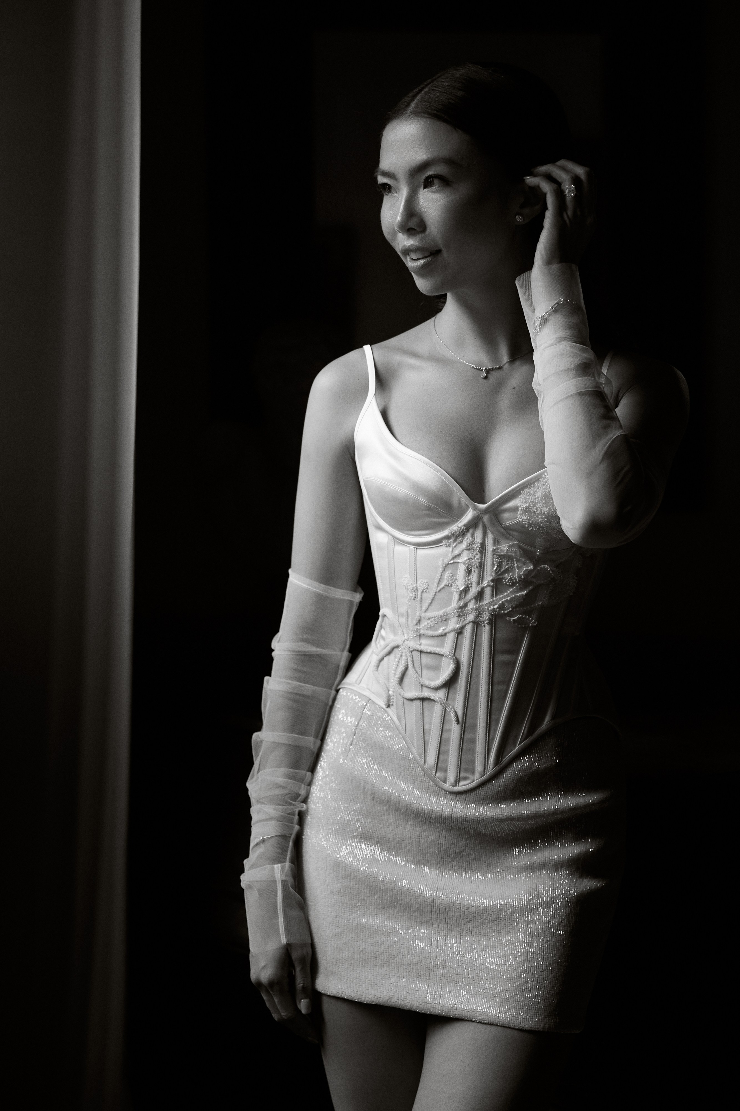 Black and white portrait of the bride beside a window 