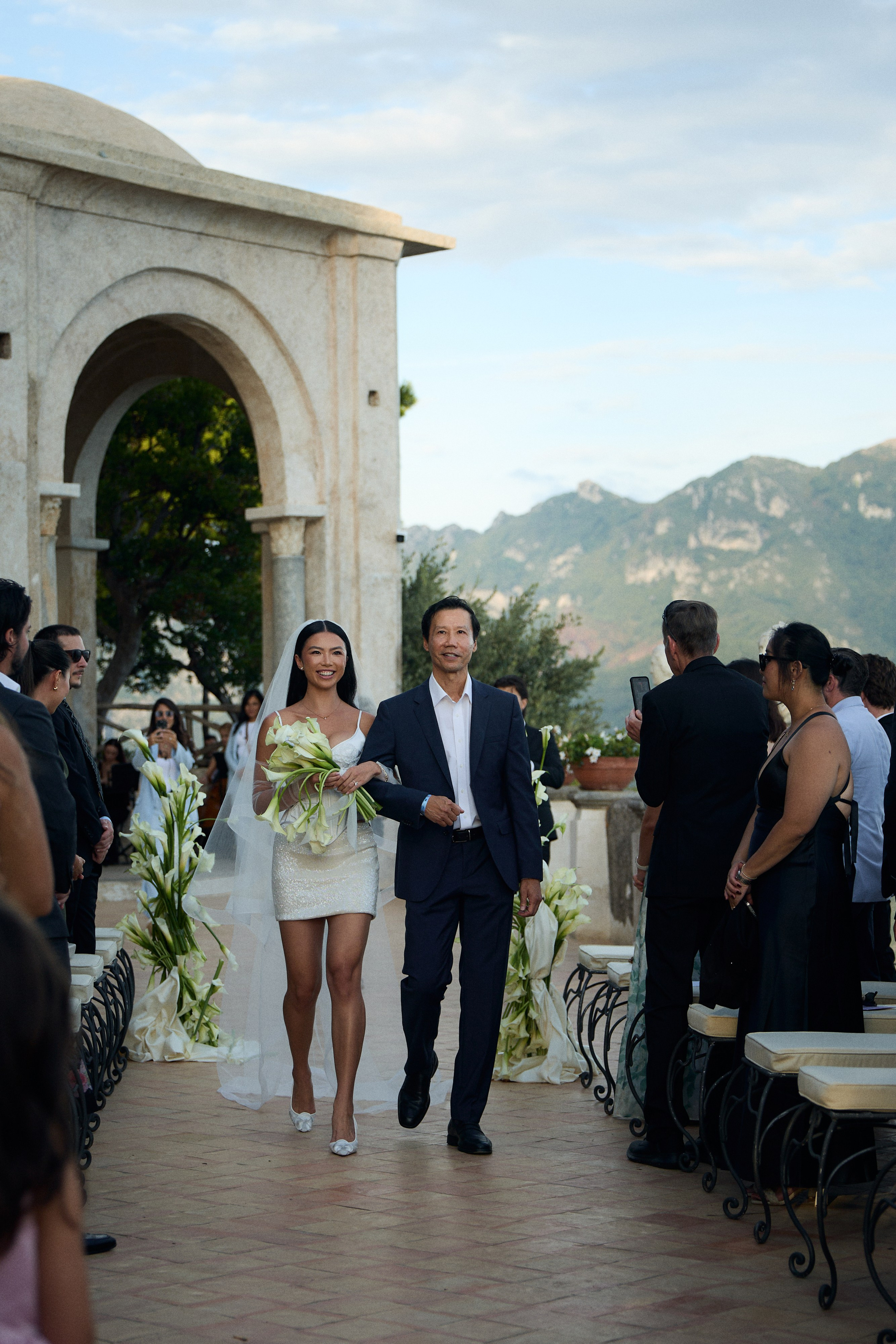 Bride arriving for the ceremony through a stone arch