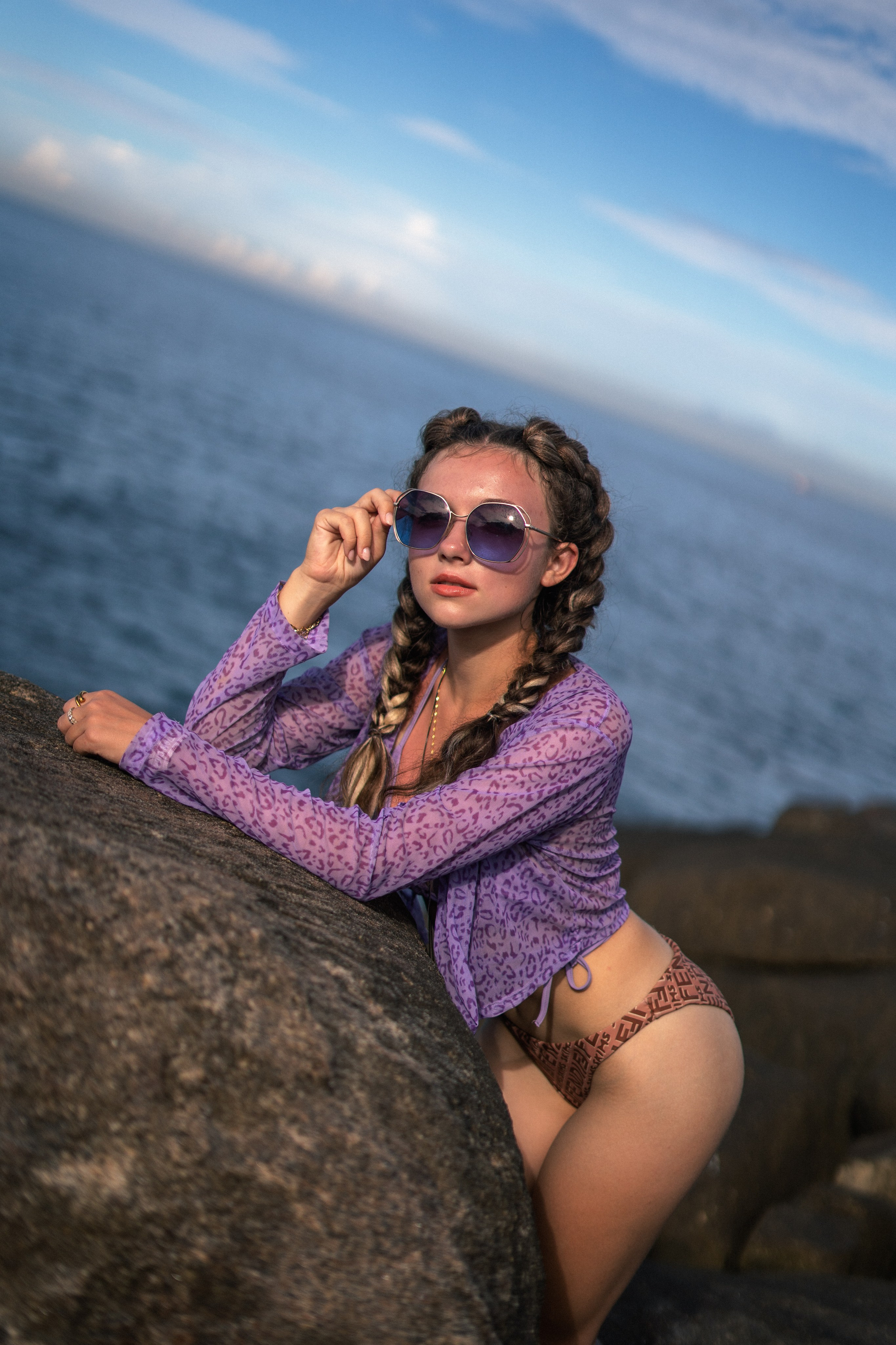 a girl in a purple swimsuit with an ocean view at sunset