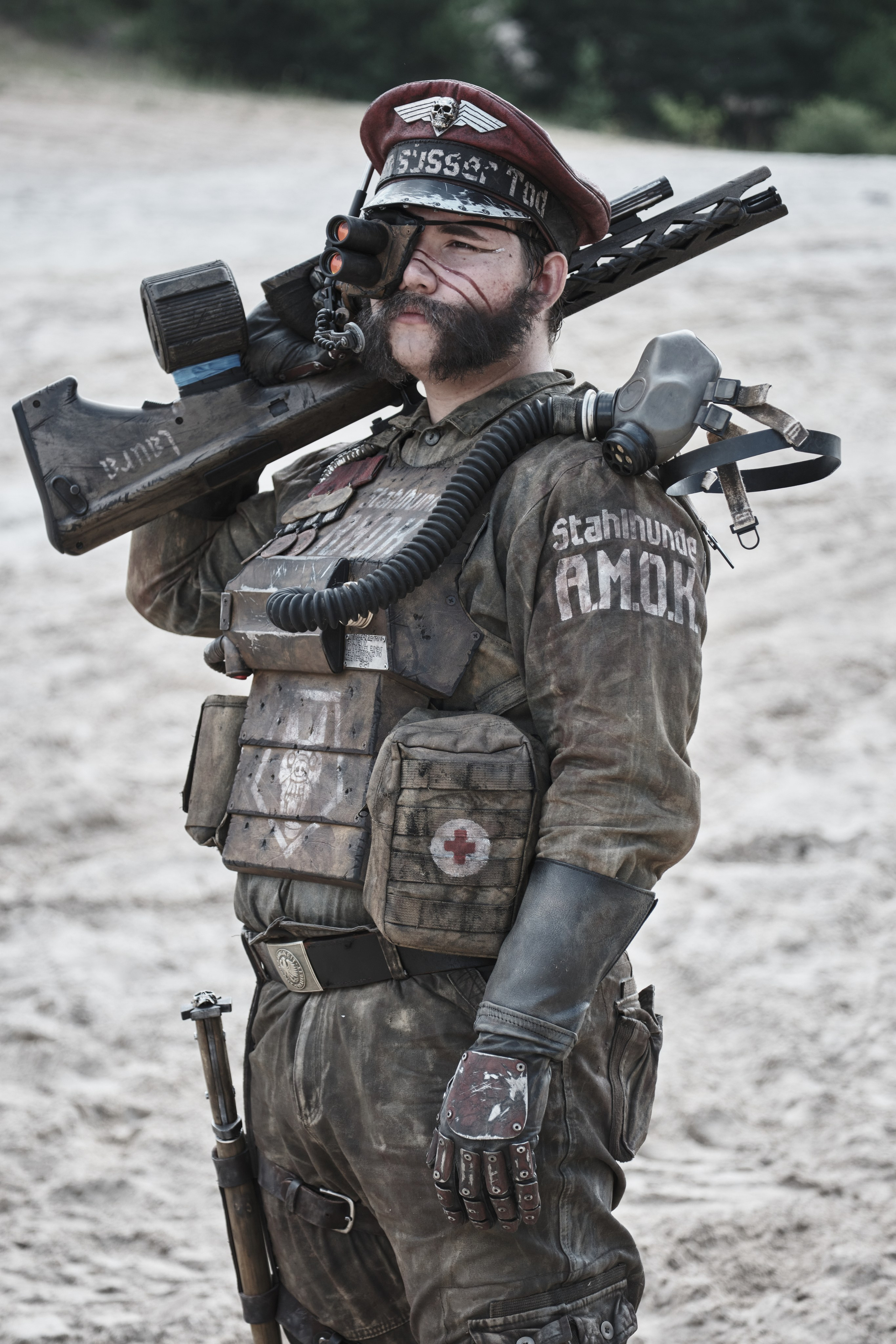 Мужчина в боевом костюме с автоматом на плече смотрит в даль в стиле пост апокалипсис