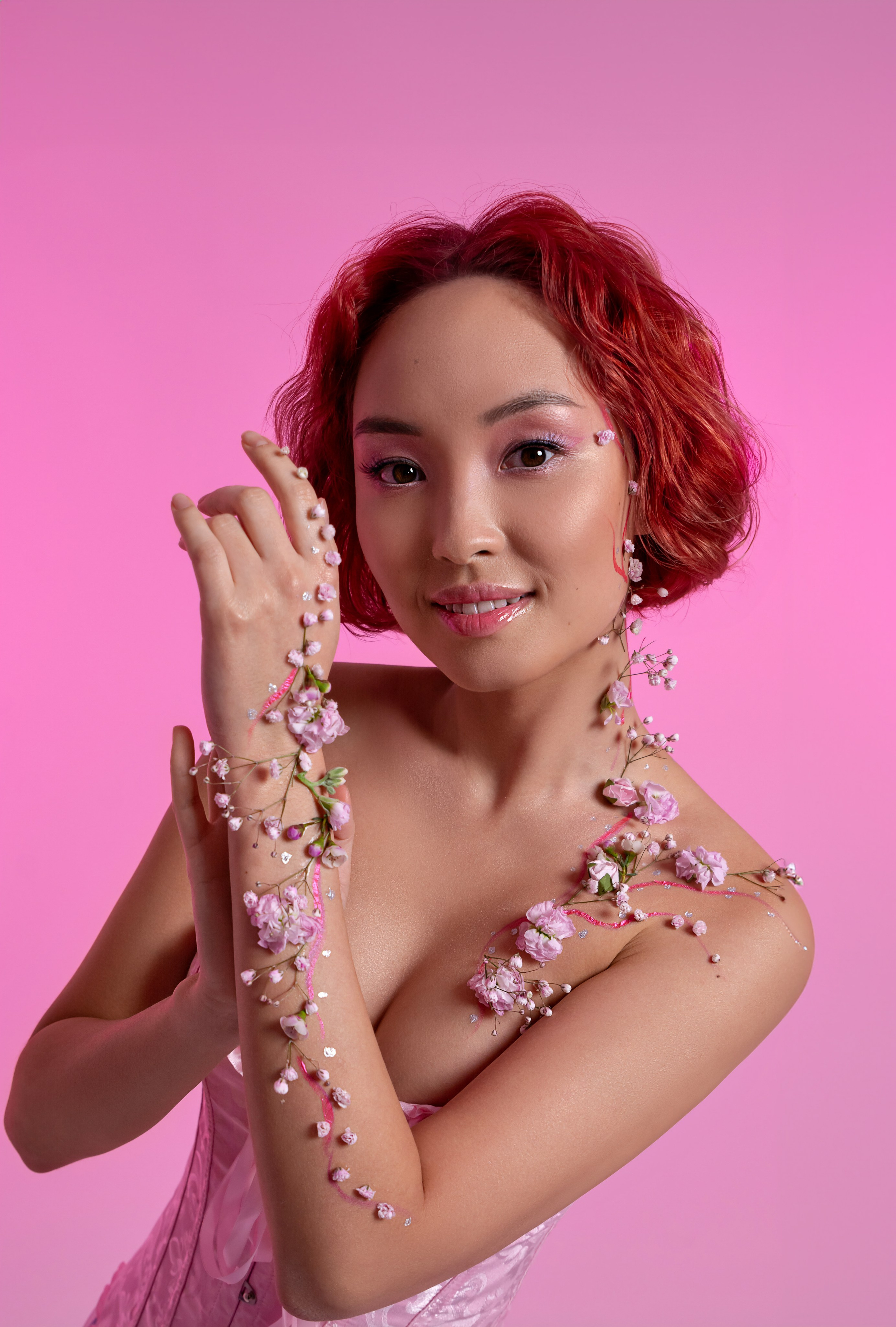 Прекрасная молодая женщина азиатской внешности с украшениями из цветов на руке и шее, олицетворяющая нежность и красоту весны.