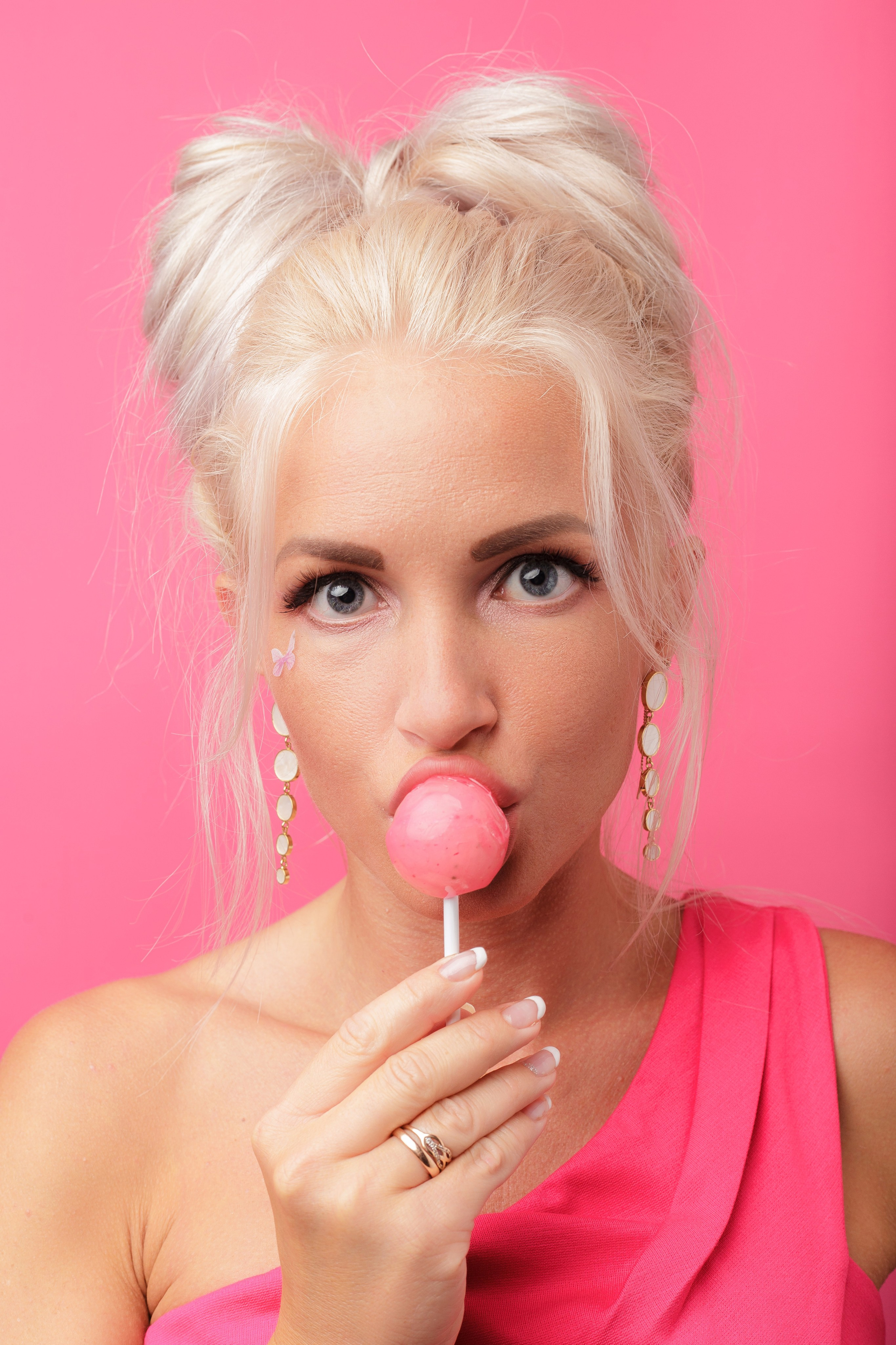 портрет блондинки с чупа-чупсом на розовом фоне