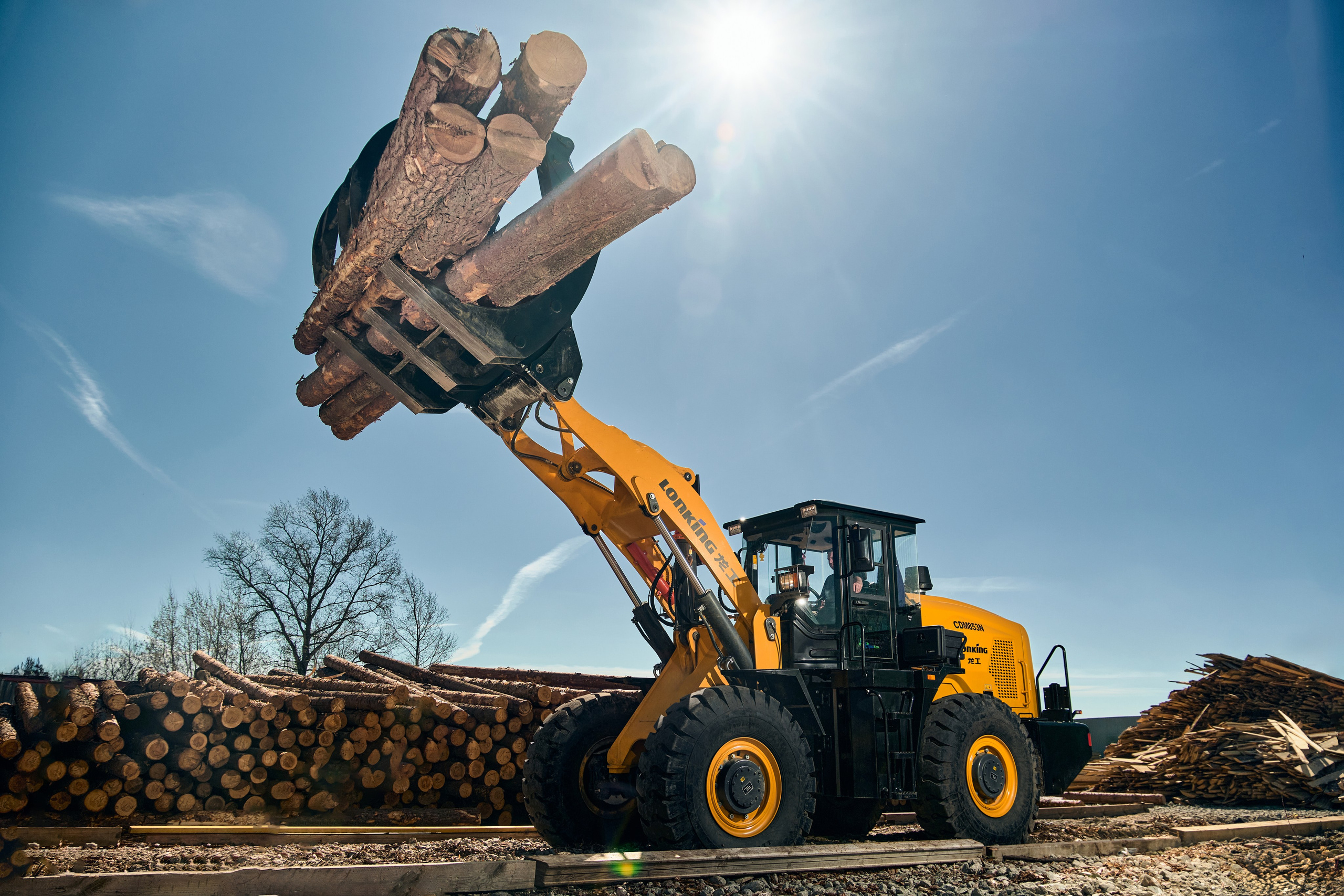 желтый трактор с бревнами 