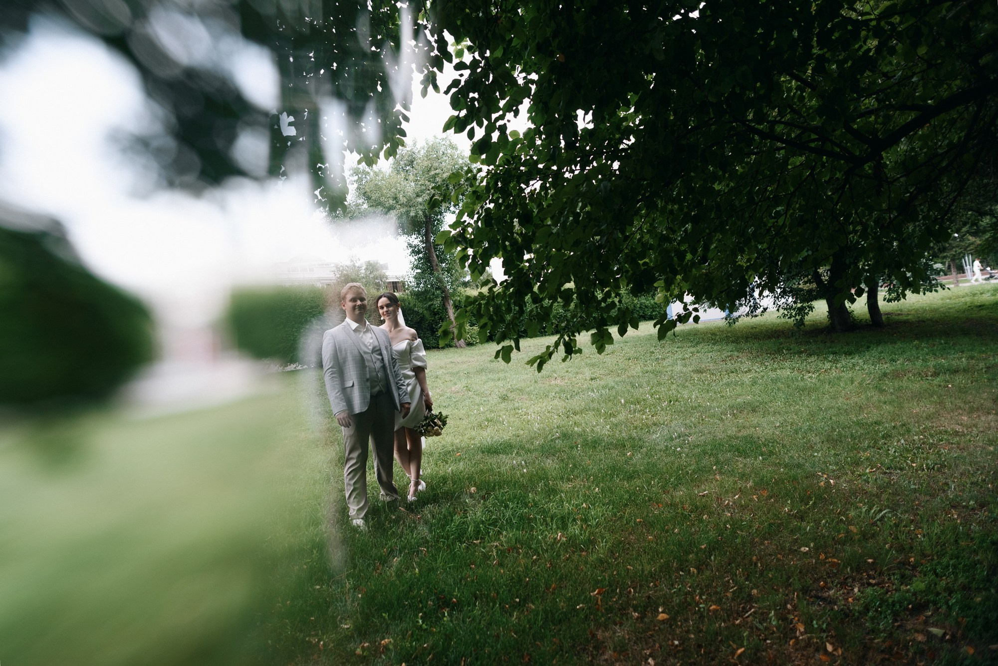 Художественное фото пары в парке через ветки деревьев, мягкий свет