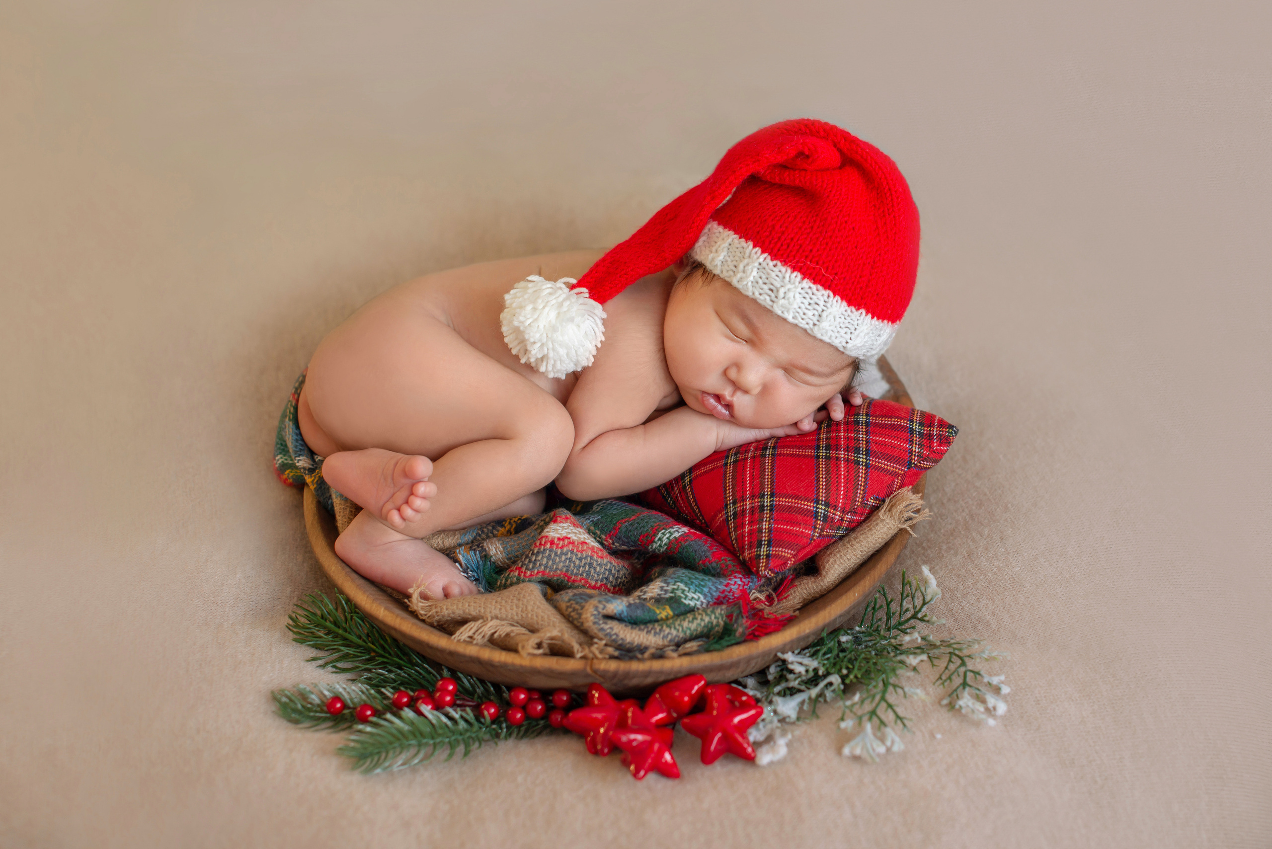 новорожденный лежит в новогоднем реквизите в новогоднем колпачке