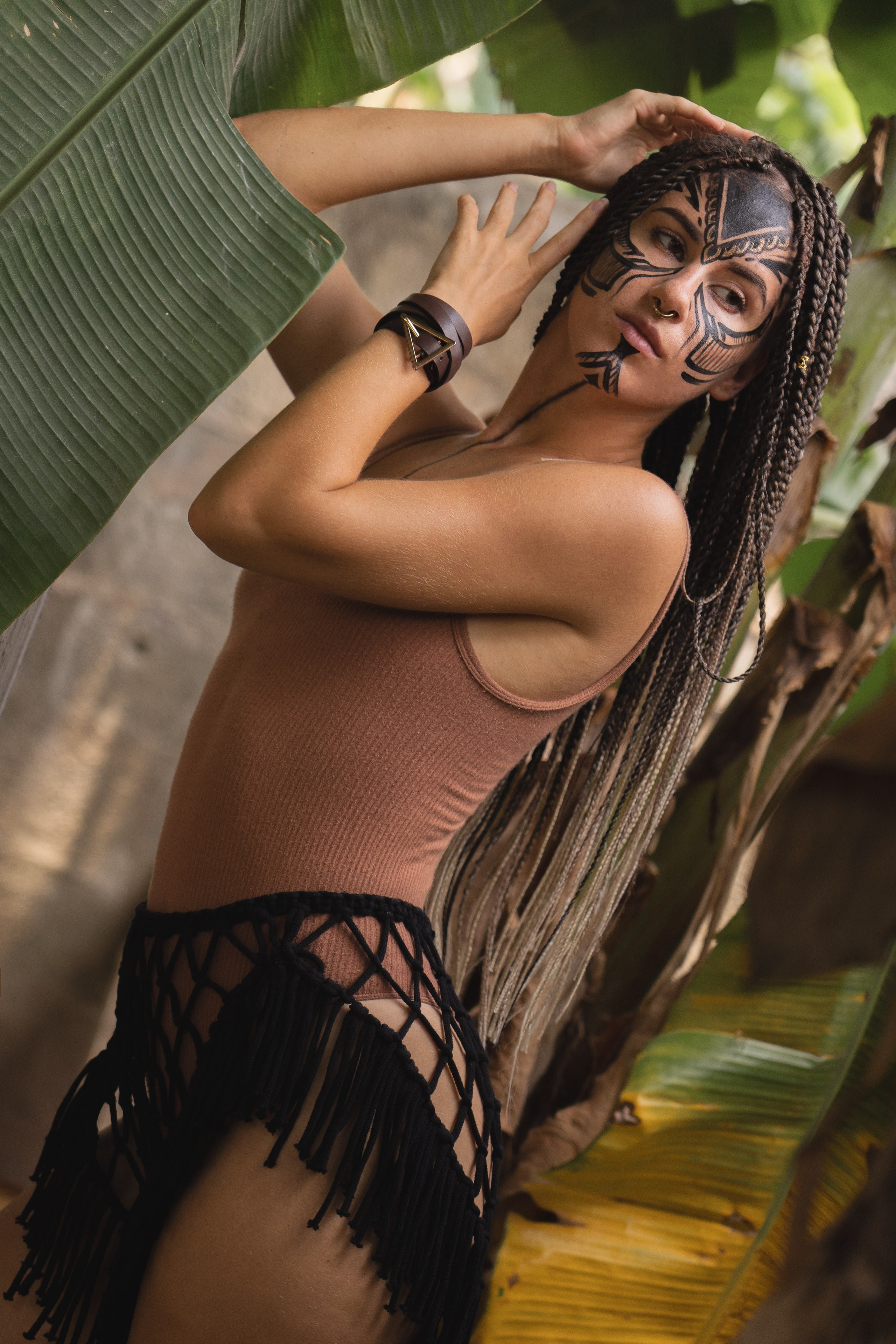 a girl with braids and patterned face paint in the jungle