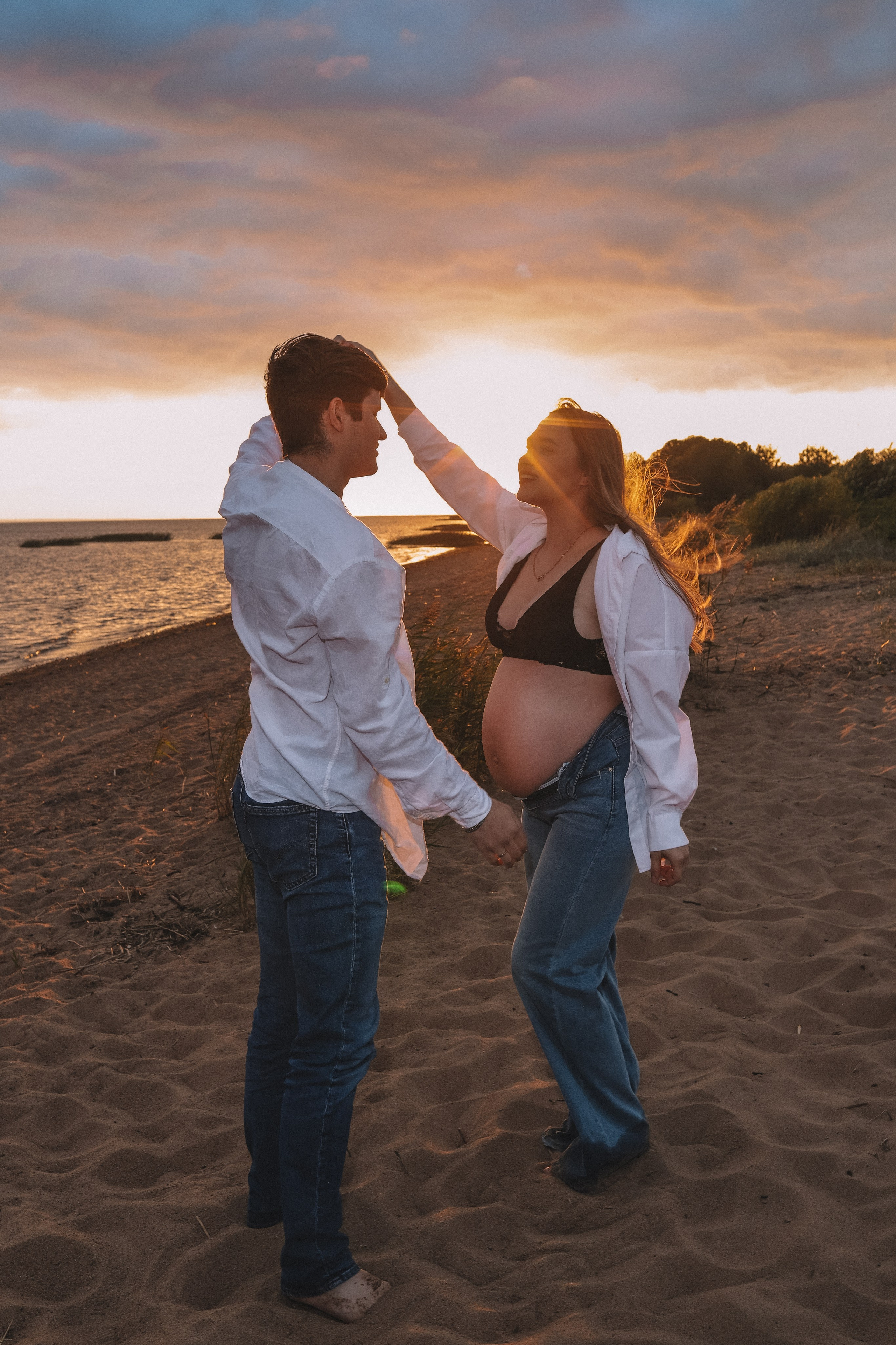 Пара обнимается и смеётся на закате