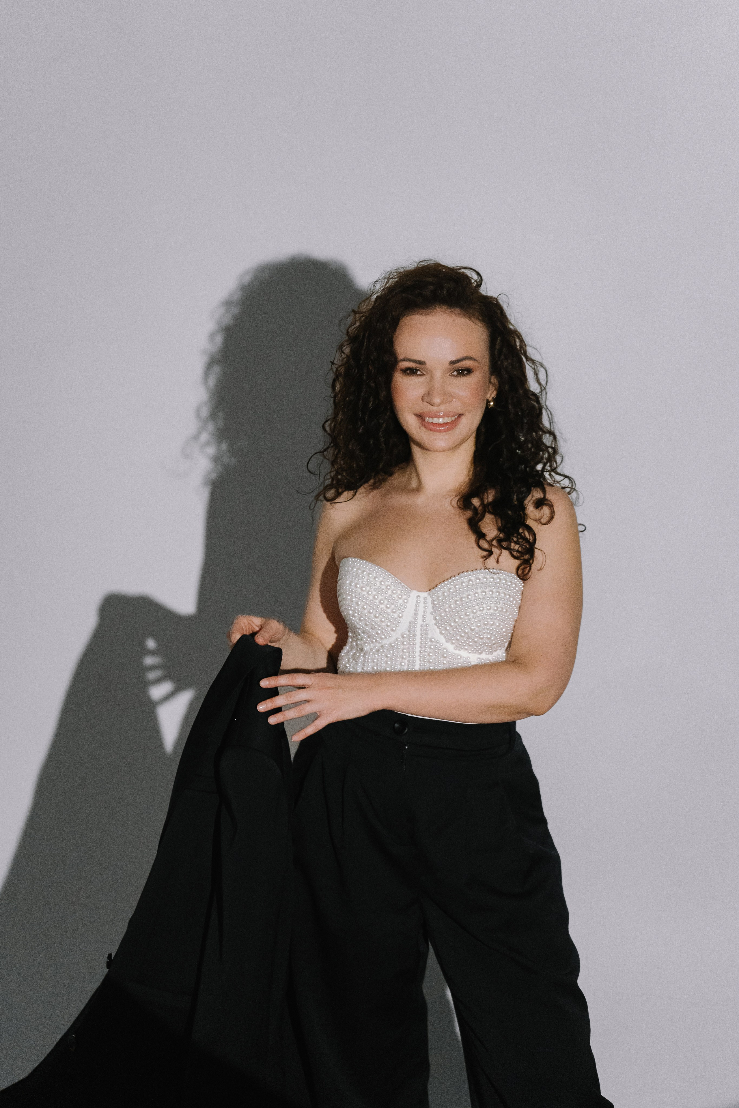 Эмоциональная портретная съемка девушки в черном костюме на сером в Анапе