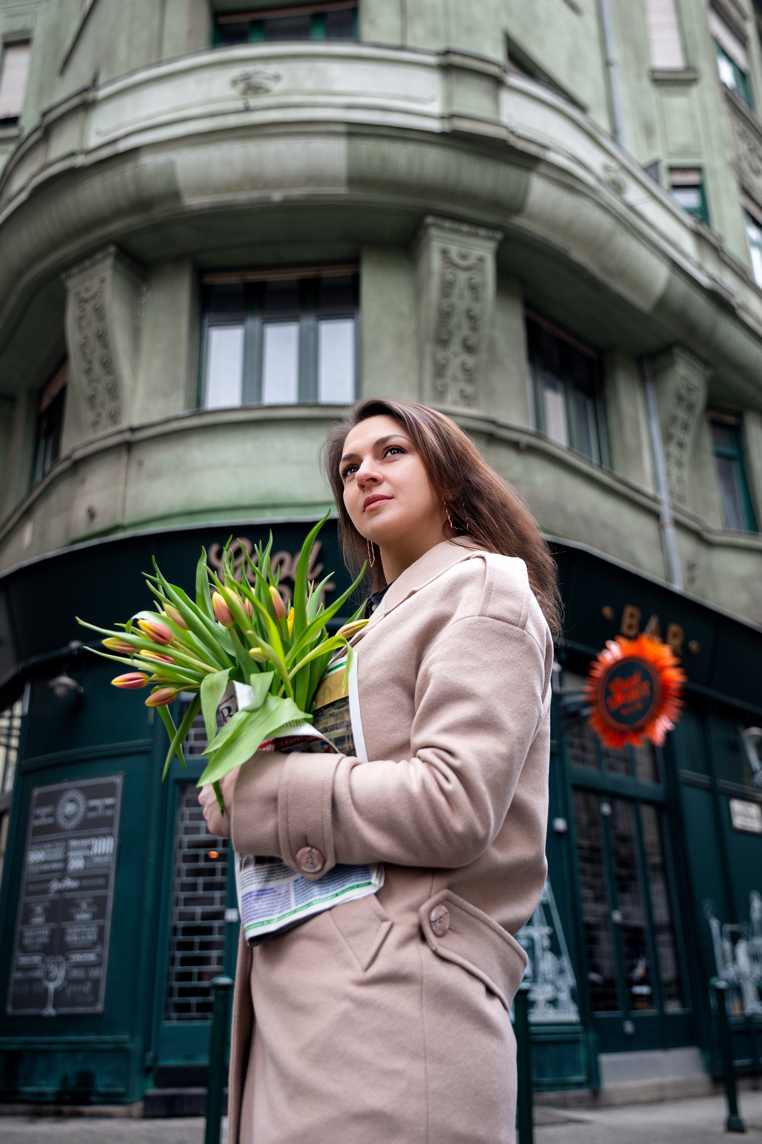 portrait of a girl with flowers in front of a green house