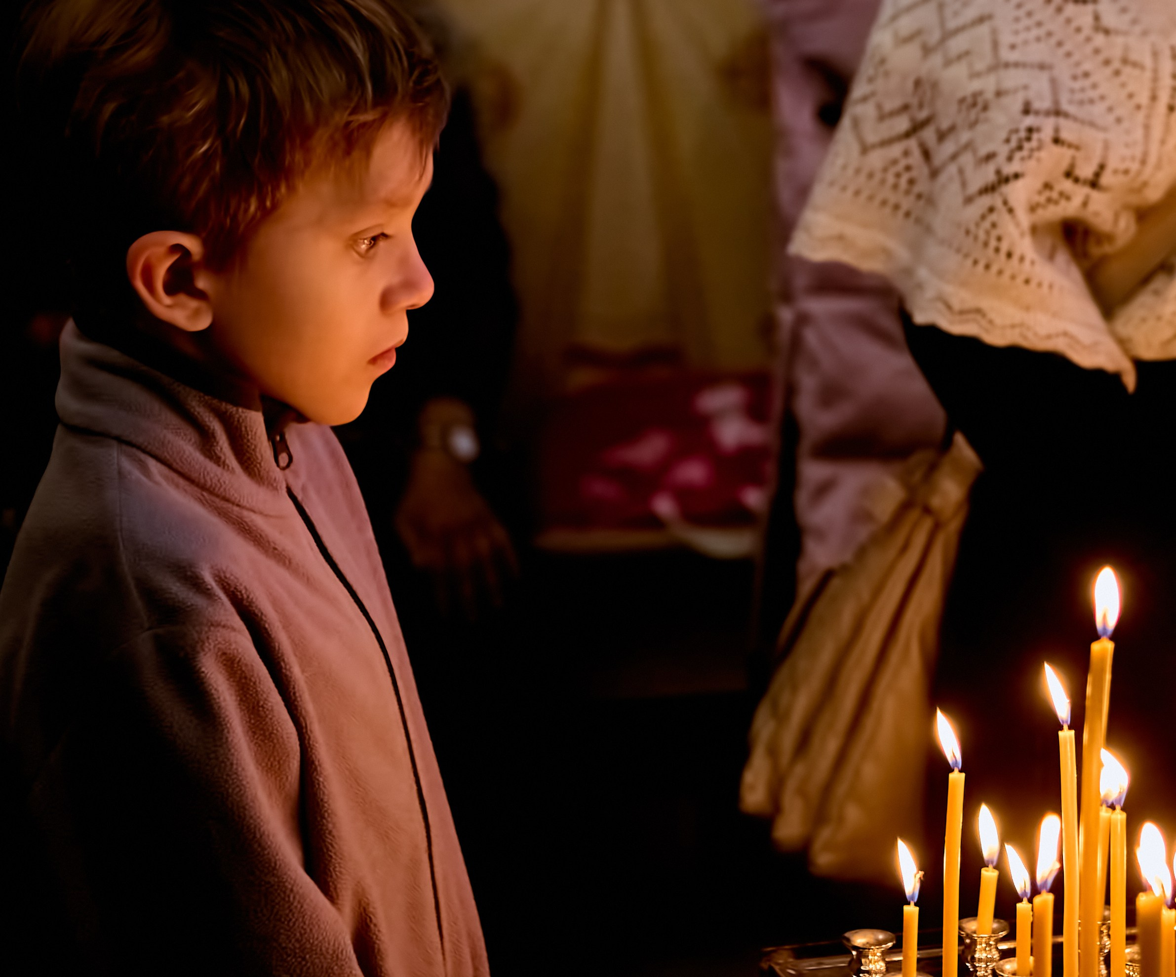 Мальчик 8-9 лет в размышлении стоит перед канунником 