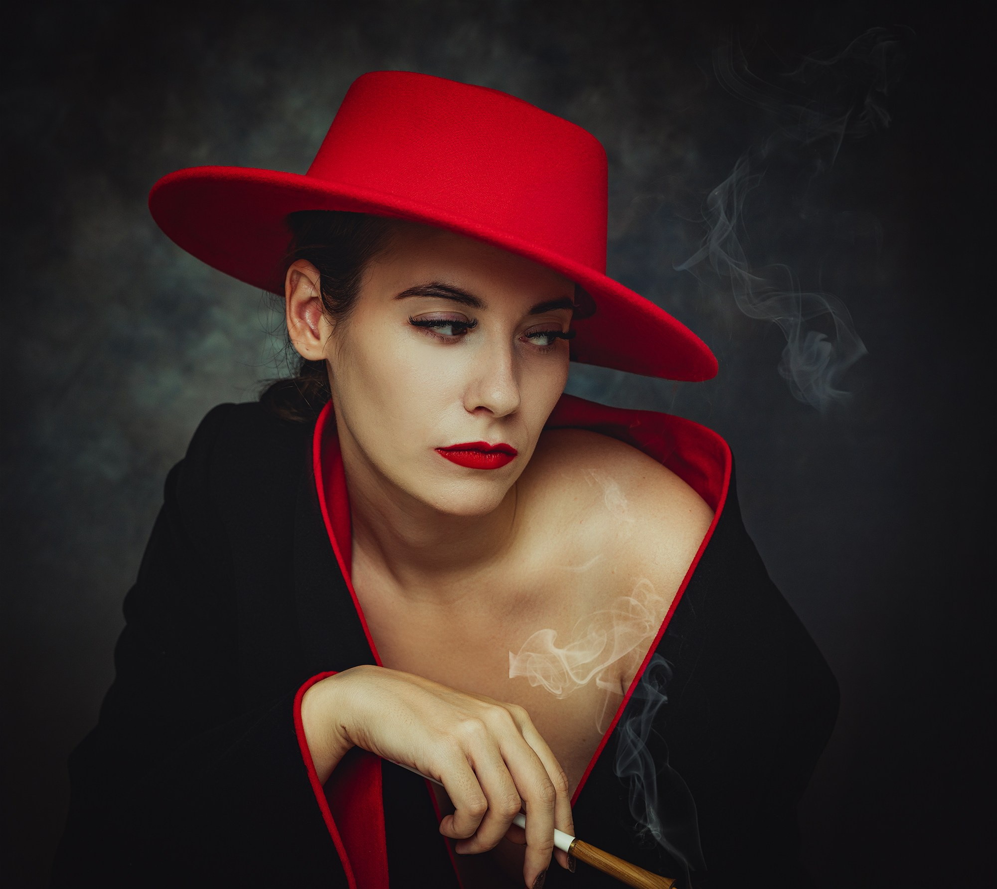 Фотография девушки в красной шляпе с дымящейся папиросой.