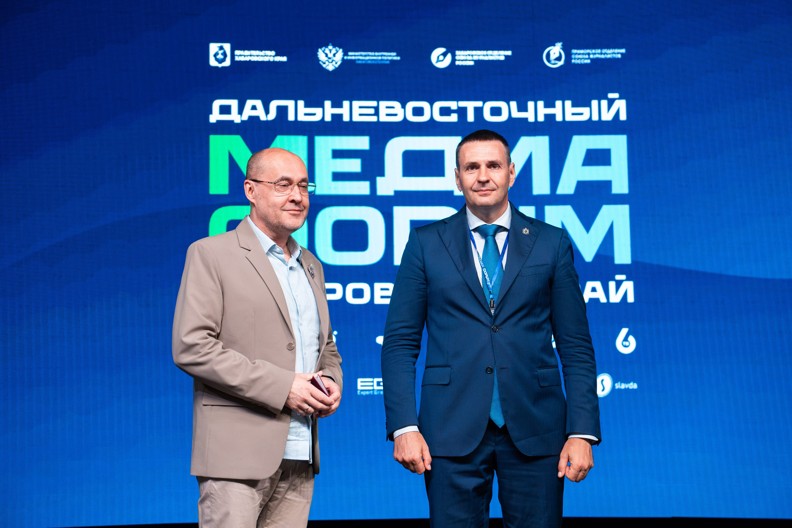 Репортажный фотограф в Хабаровске Дмитрий Дергачев запечатлел торжественное вручение благодарственного письма участнику в синем костюме на Дальневосточном медиафоруме.