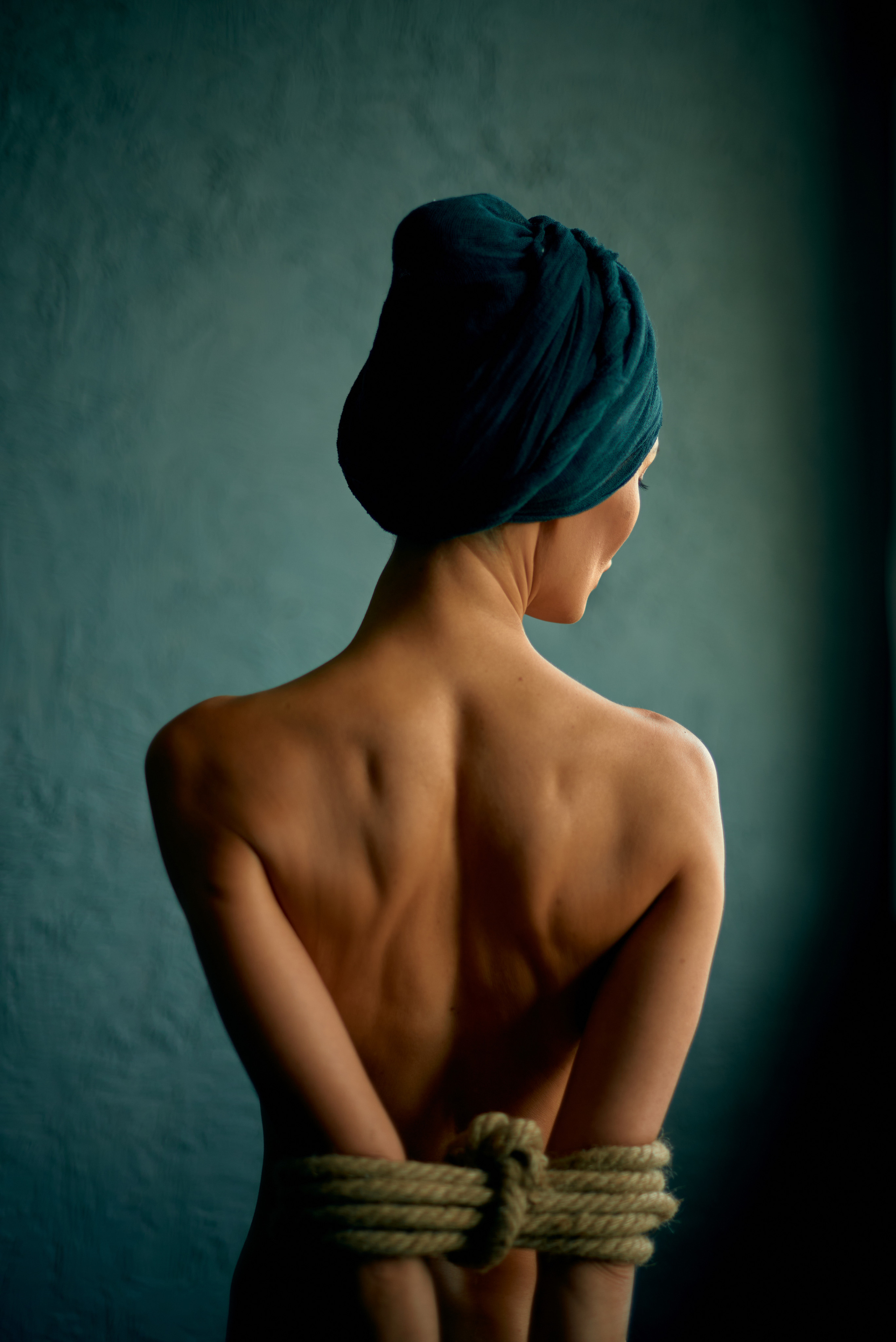 Портрет со спины обнаженной девушки в тюрбане со связанными руками