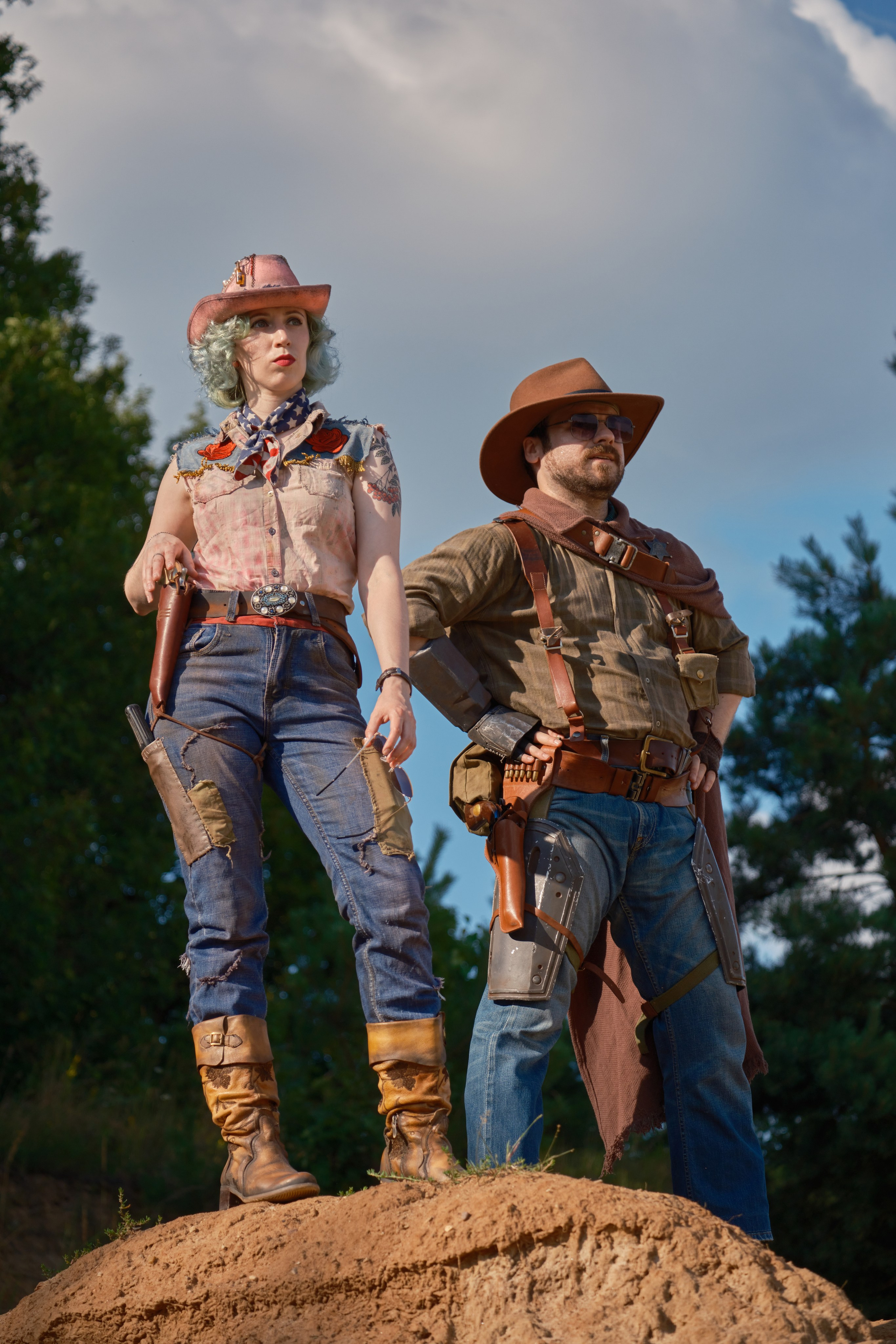 Мужчина и девушка в ковбойских шляпах стоят на горе