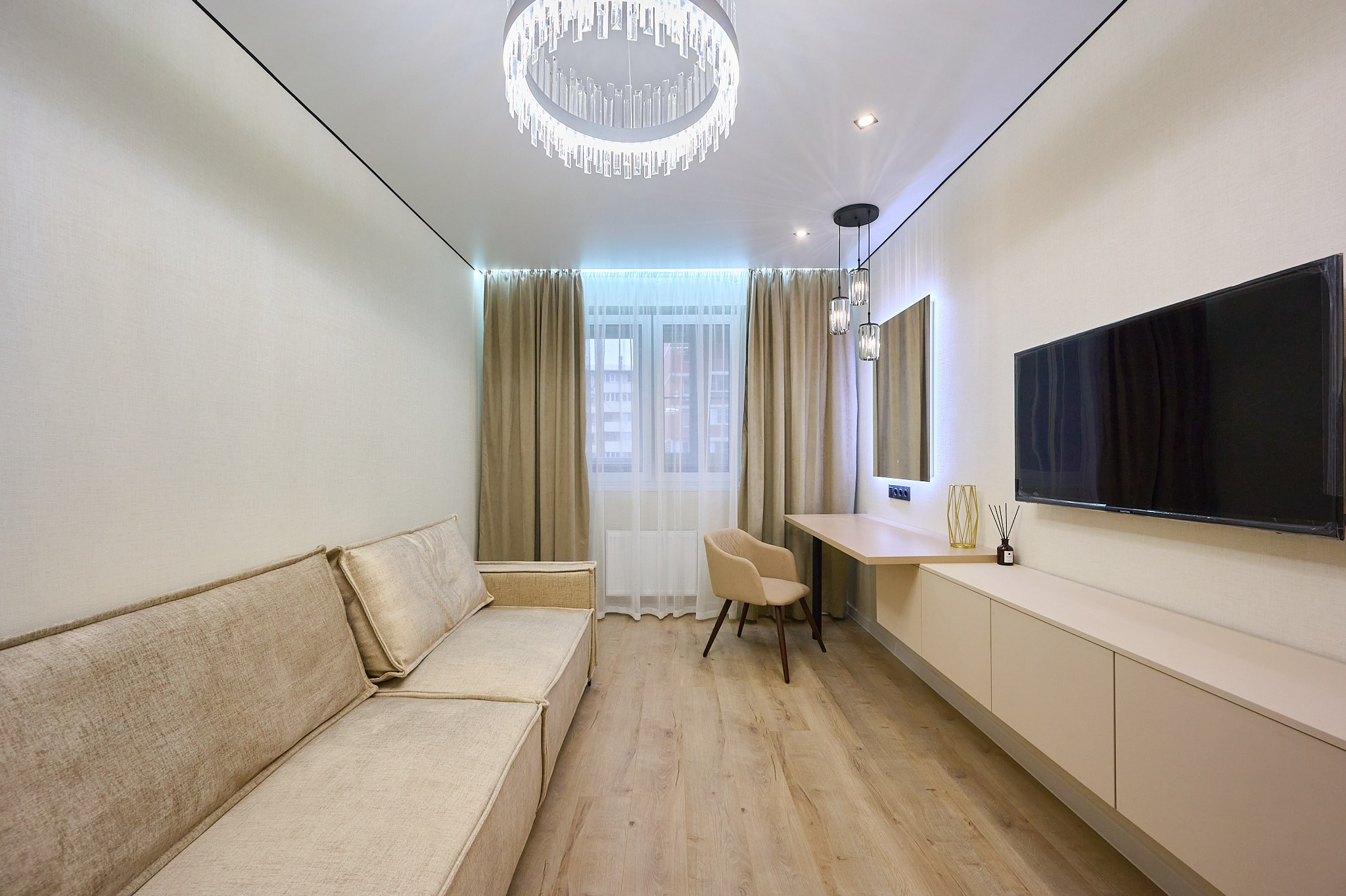 комната белые обои светлый диван комод белый телевизор бежевые шторы столик с креслом 