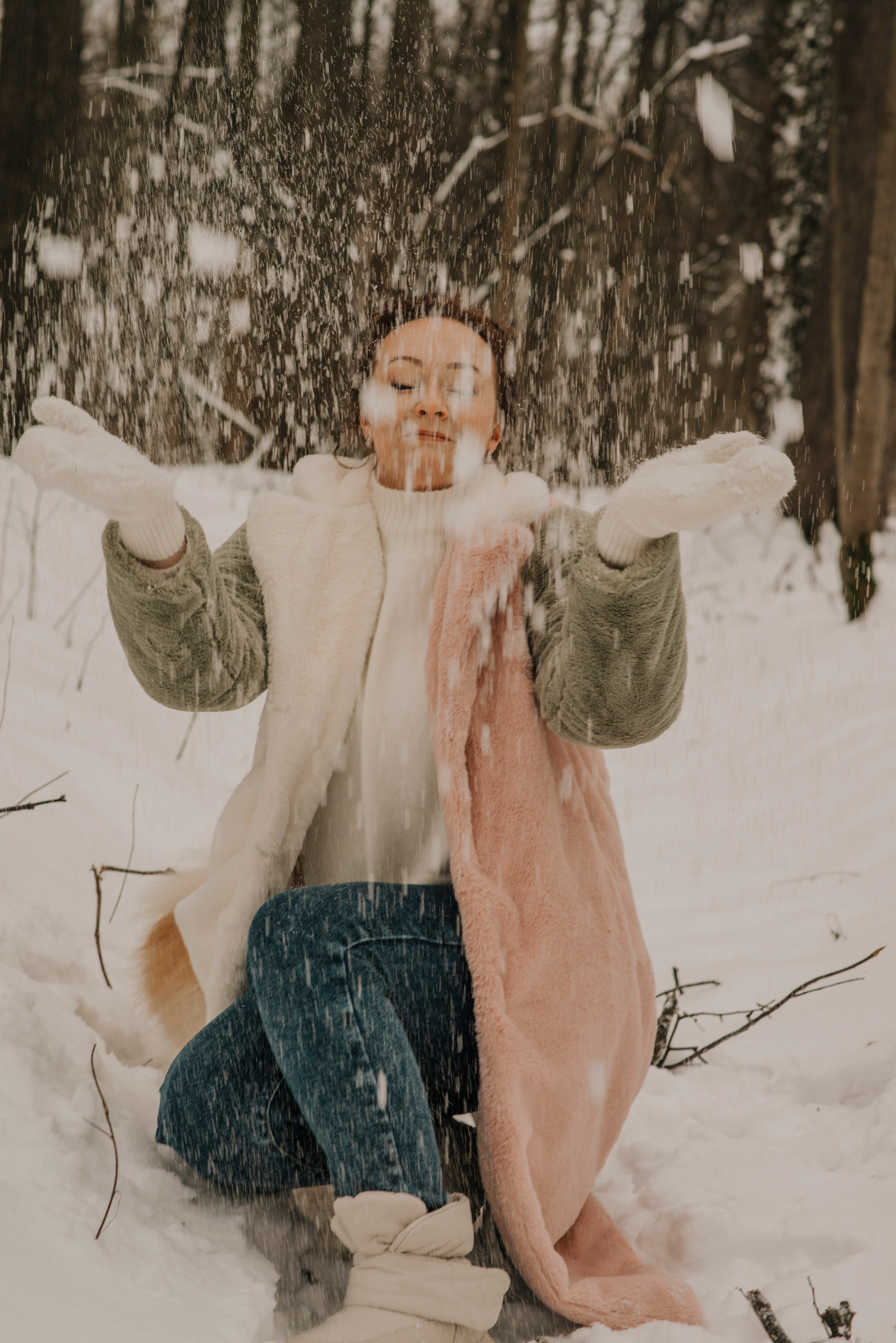 Девушка с рыжими волосами в бело-розово-зеленой шубе и белых варежках в снегу