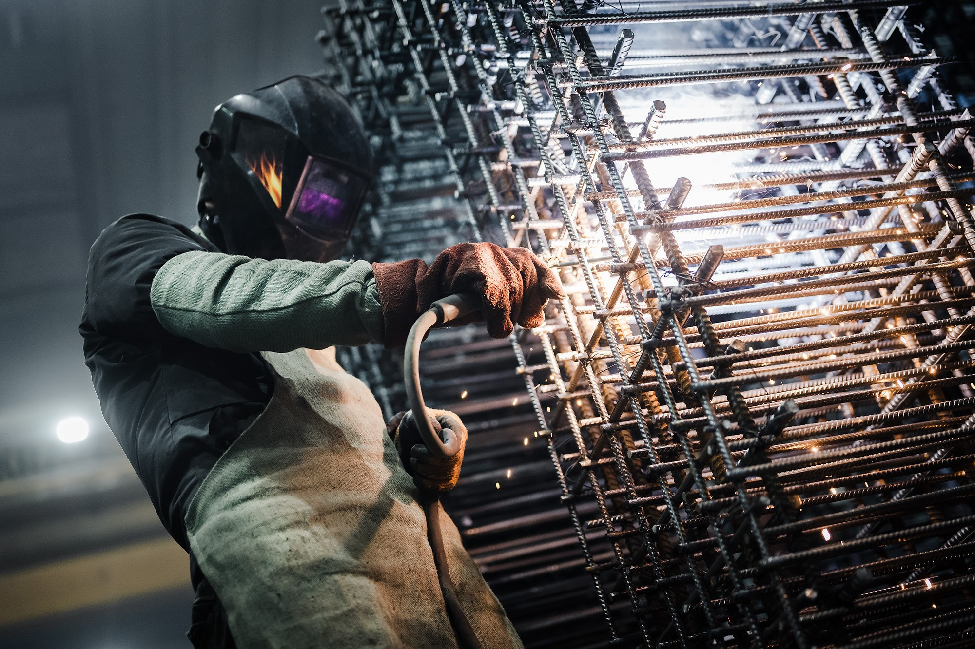 Сварщик делает сварку каркаса для защитного сооружения.
