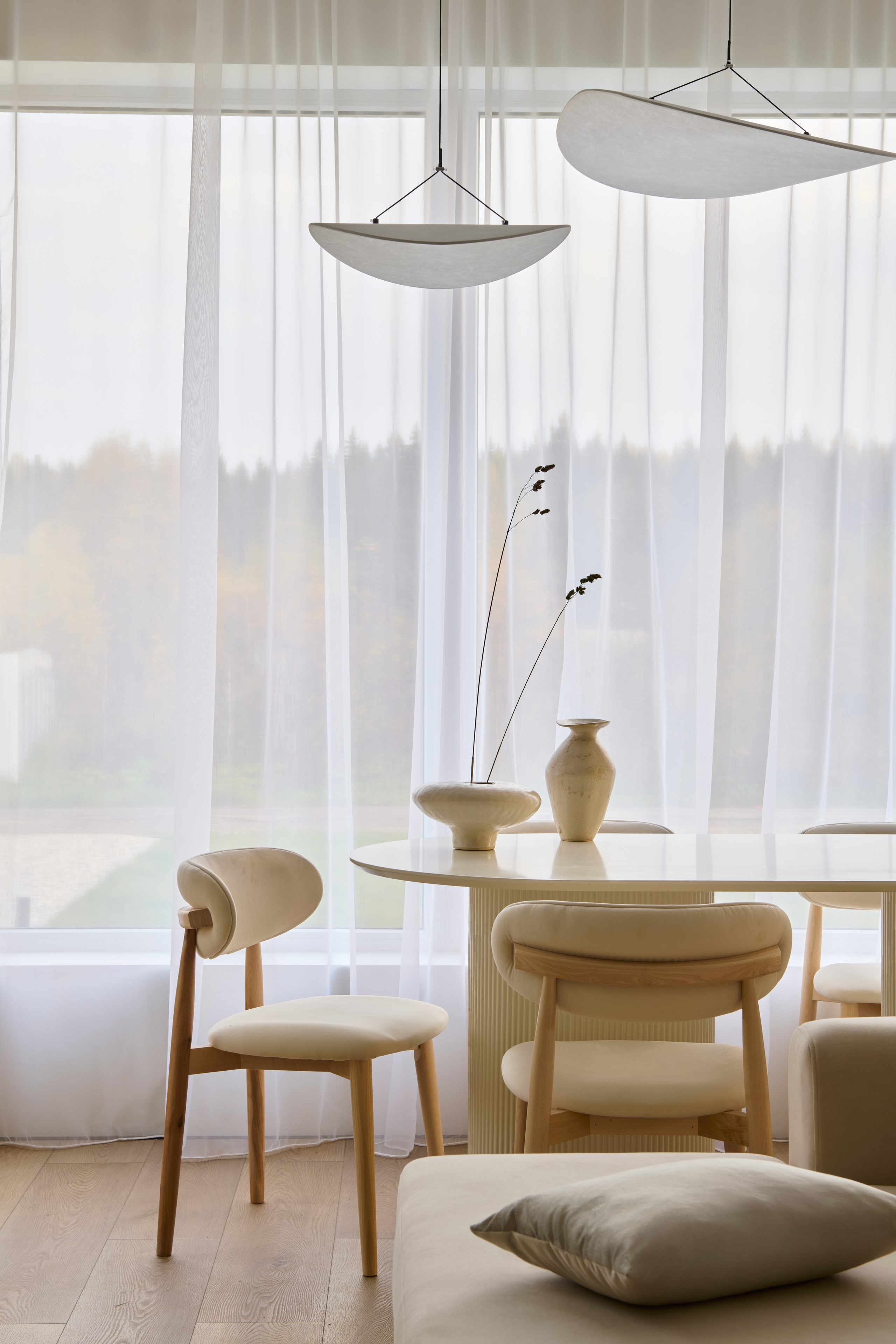 Обеденная зона у прозрачных штор, свет и мягкие формы мебели