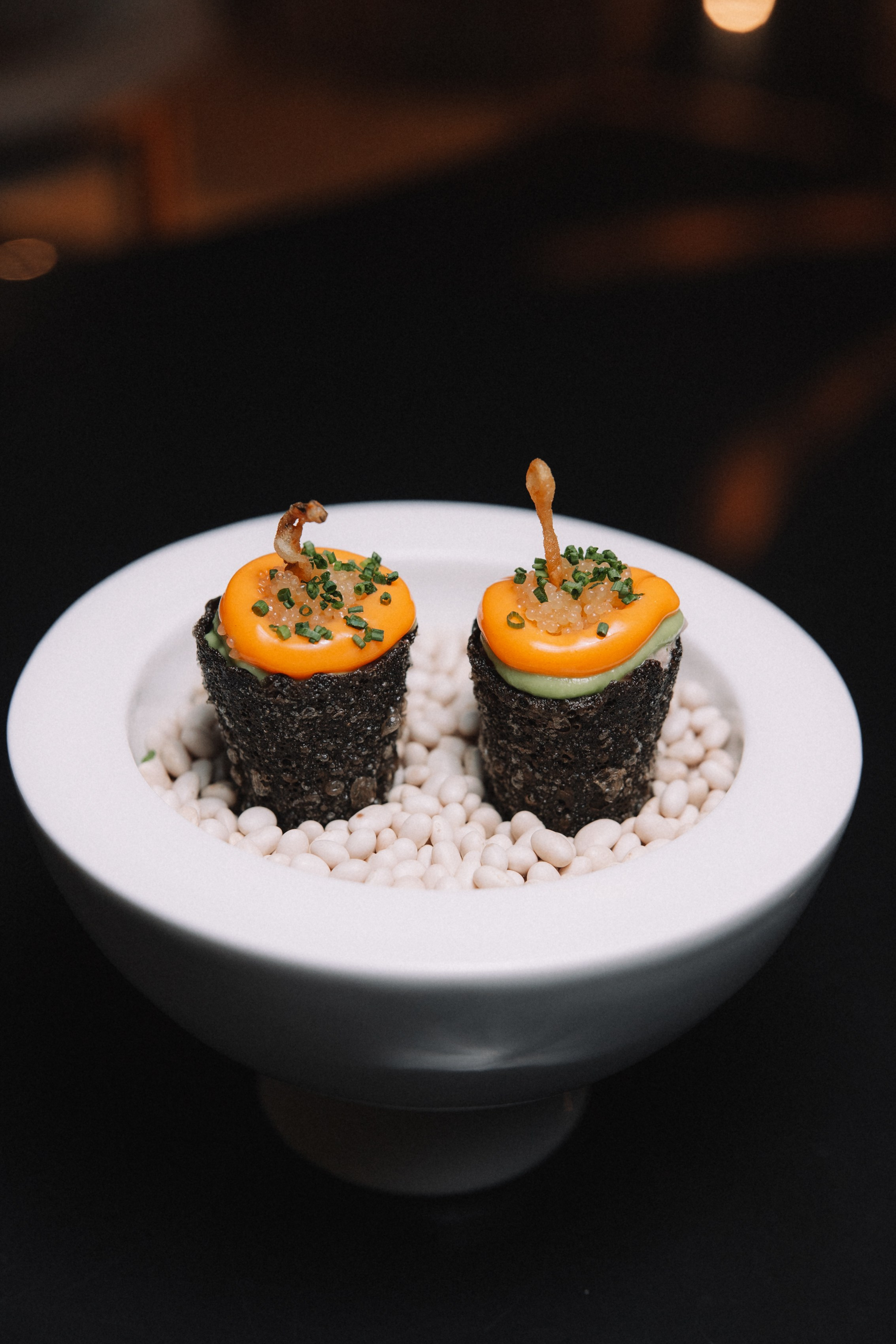 Детали: Две миниатюрные закуски, оформленные в виде роллов, на подушке из белых камней.