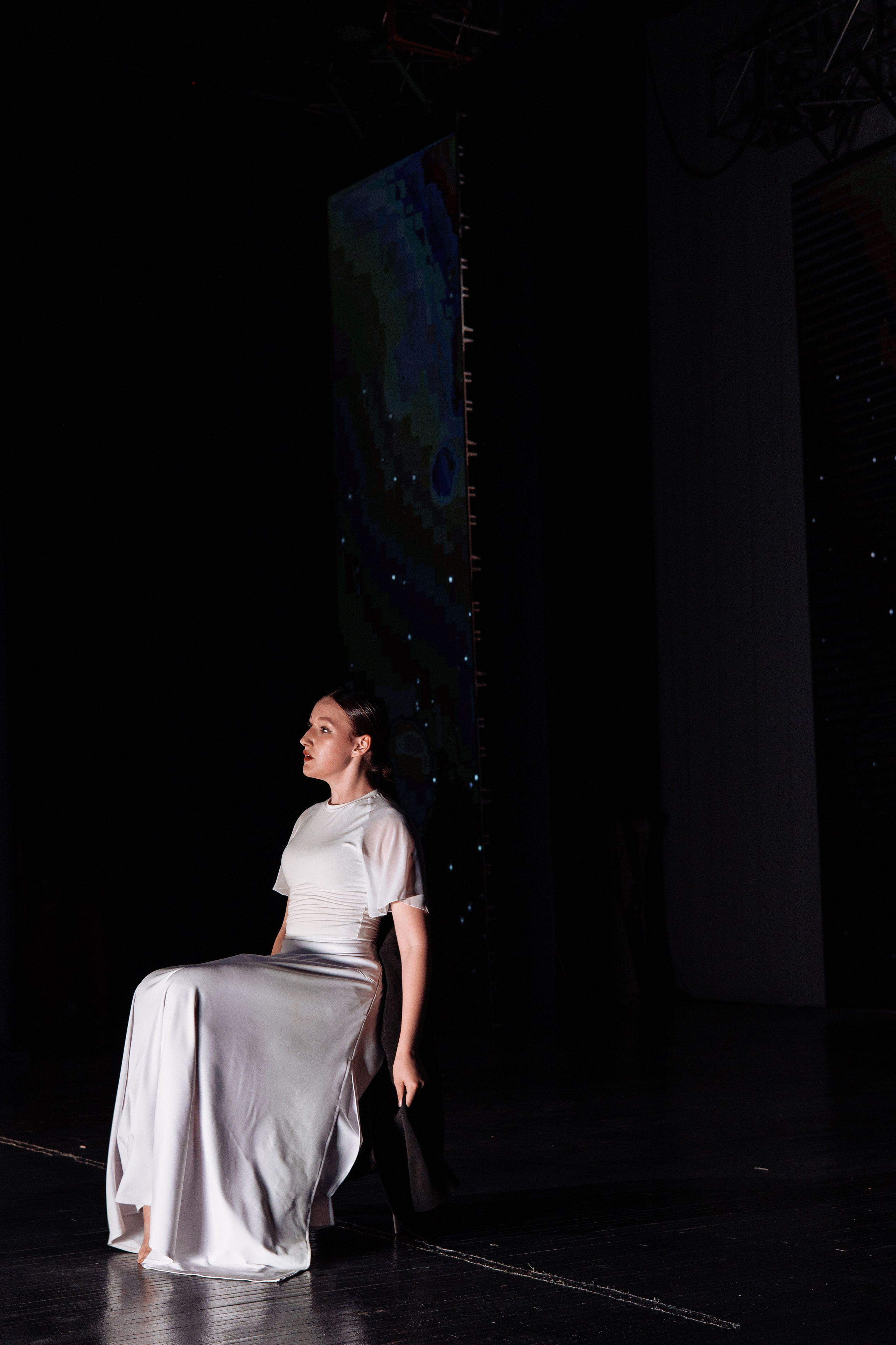 Девушка в белом платье сидит на сцене — финал выступления в рамках Зазеркалья.