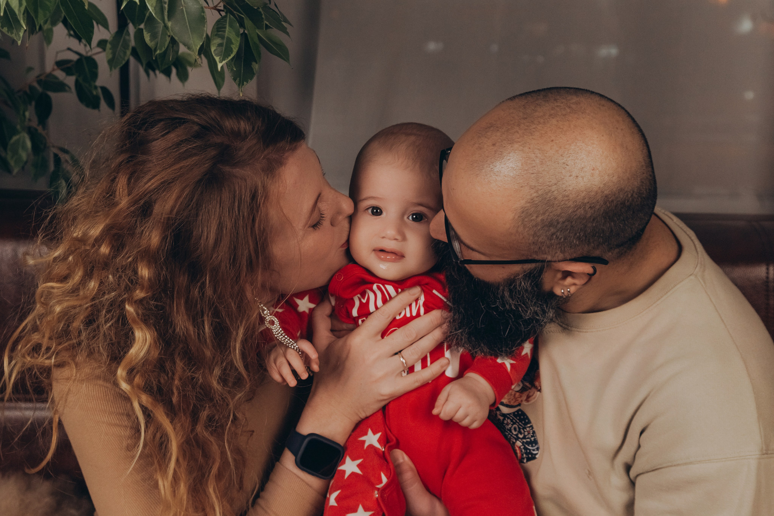 Родители целуют малыша на руках, крупный семейный момент.