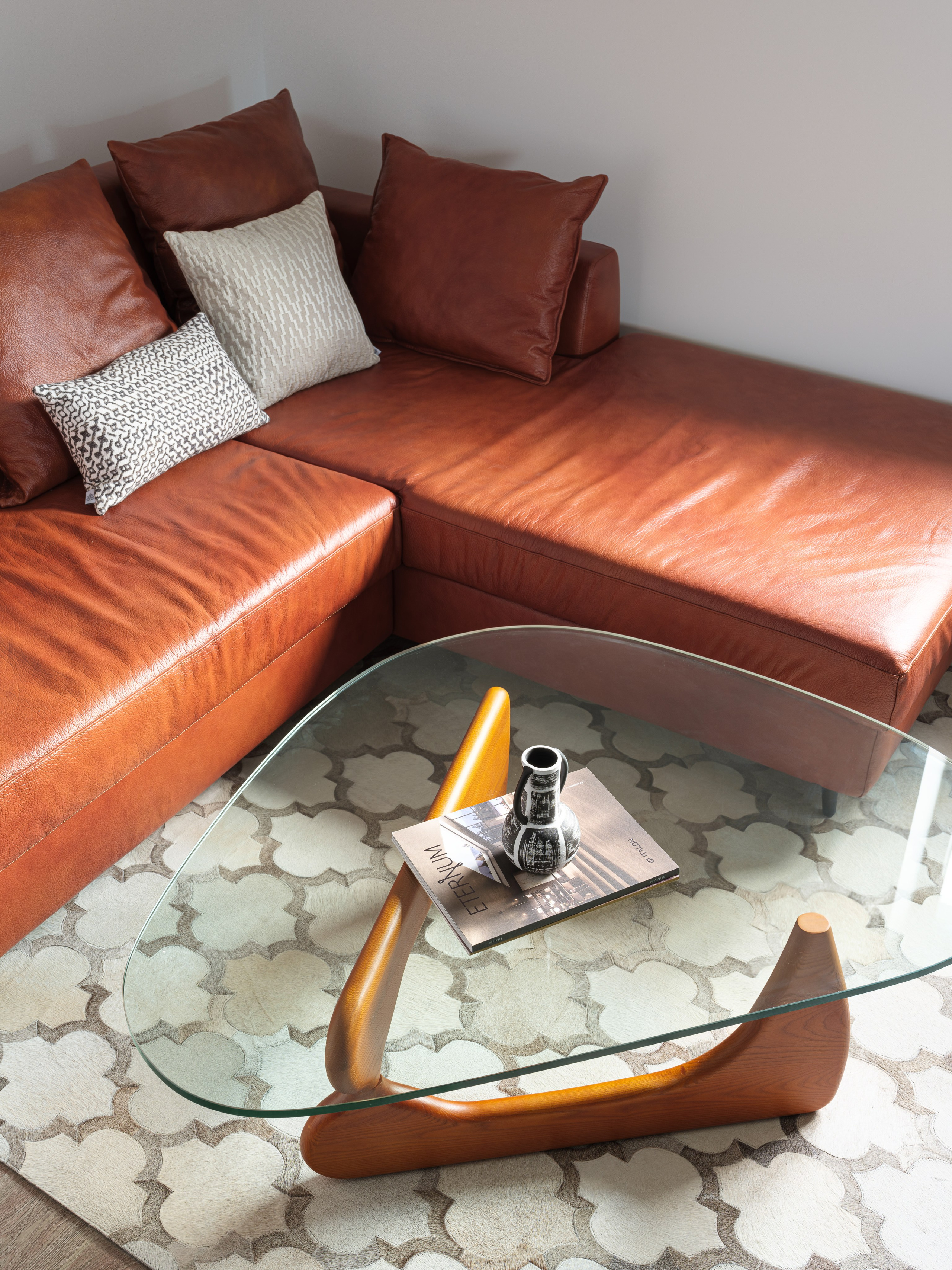 Современный дизайн интерьера с уютным кожаным диваном и стильным стеклянным столиком. Интерьер сочетает минимализм и комфорт. Фото работы Татьяны Диденко и Сергея Денисенко, стилистика Натальи Якушевой.