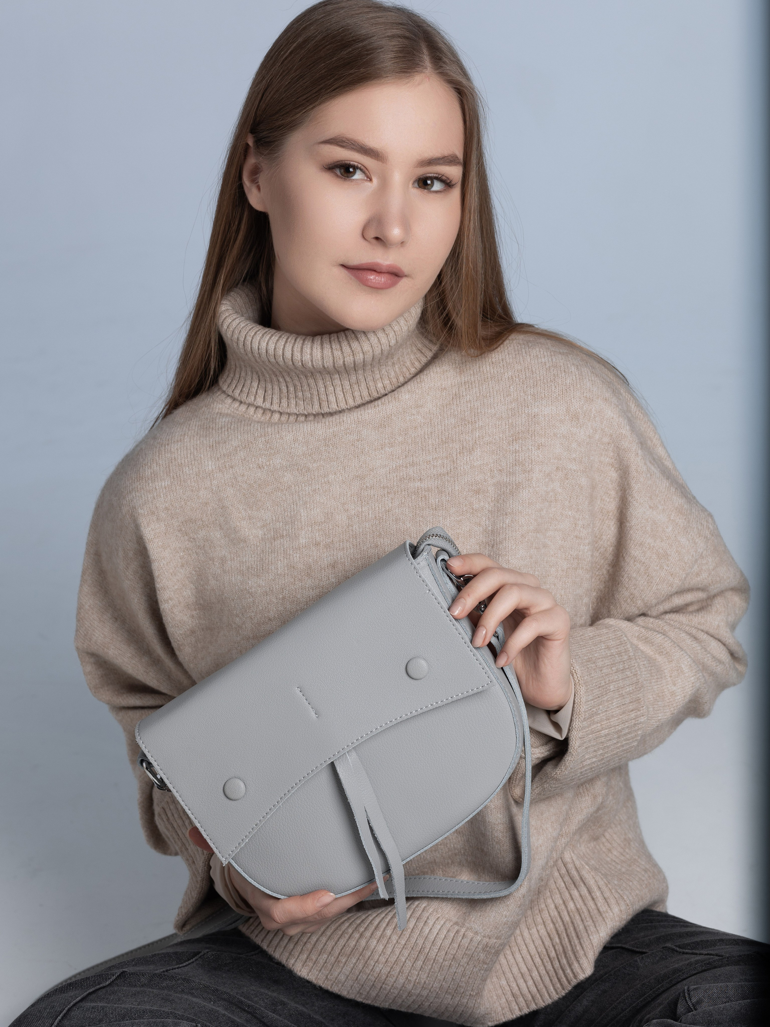 Модель держит в руках женскую сумочку