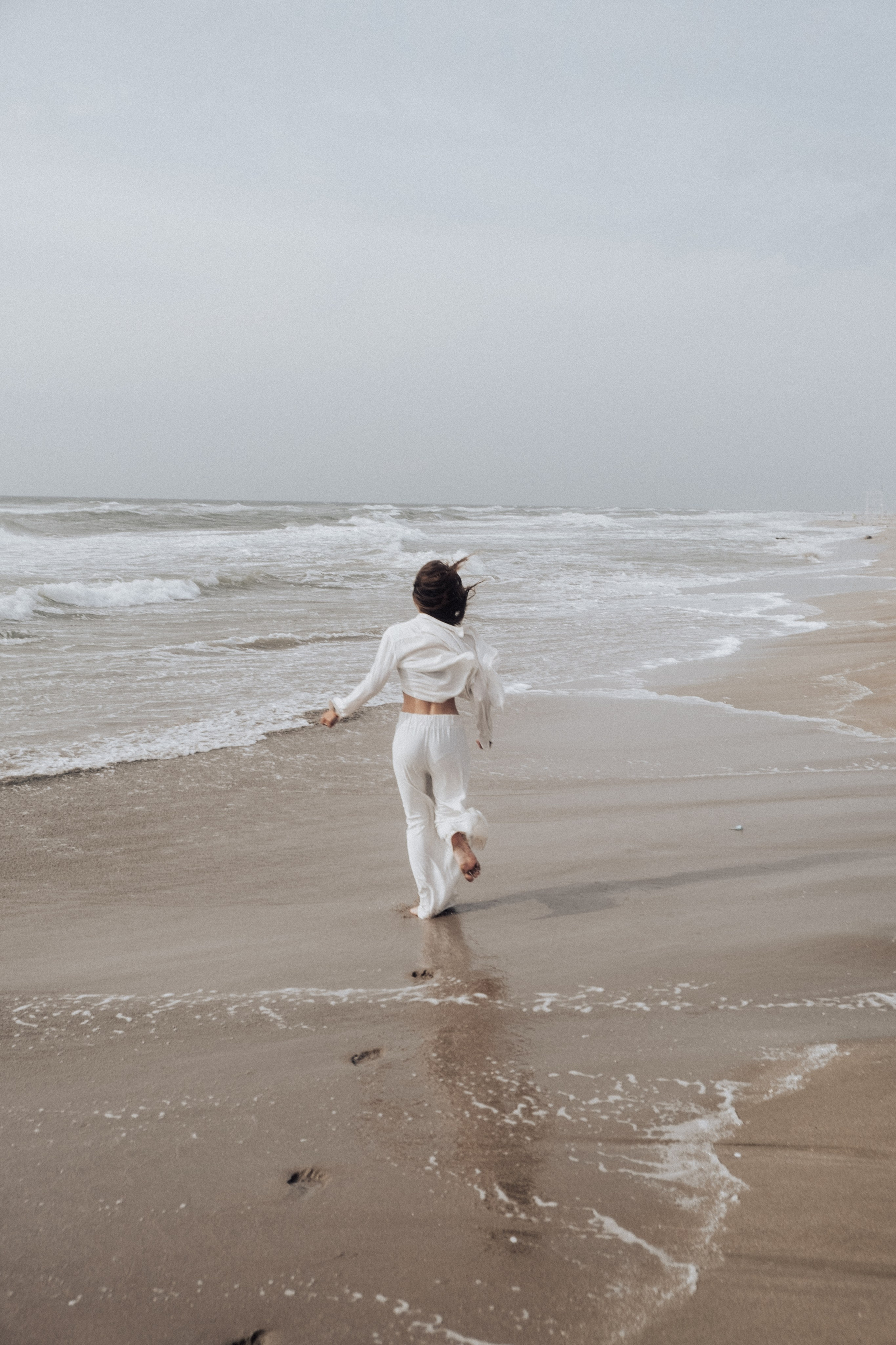 Фотоснимок бегущей девушки вдоль пляжа