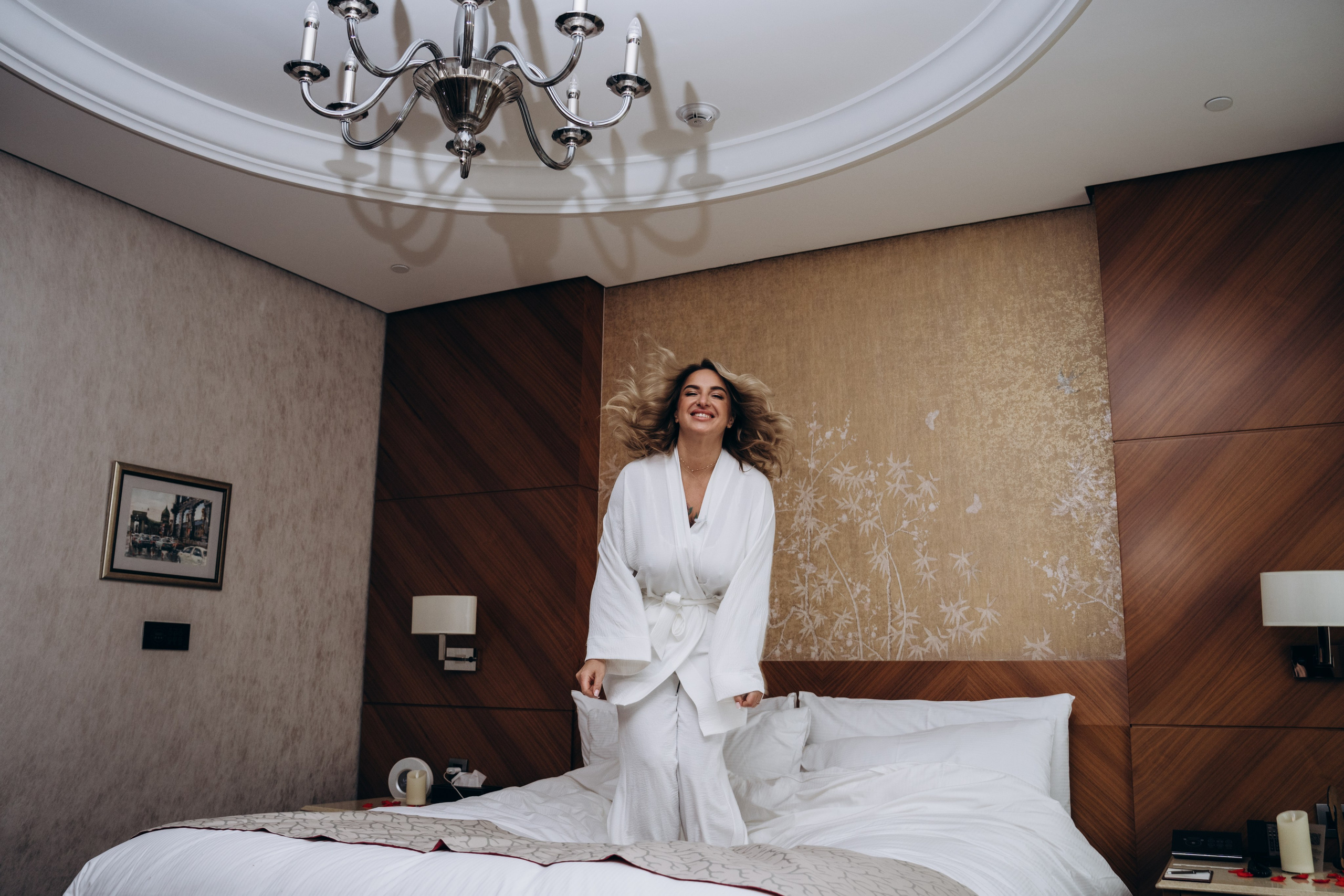 Невеста сидит в кресле, пока визажист наносит ей макияж — профессиональная свадебная фотосъемка в Москве с акцентом на подготовку.