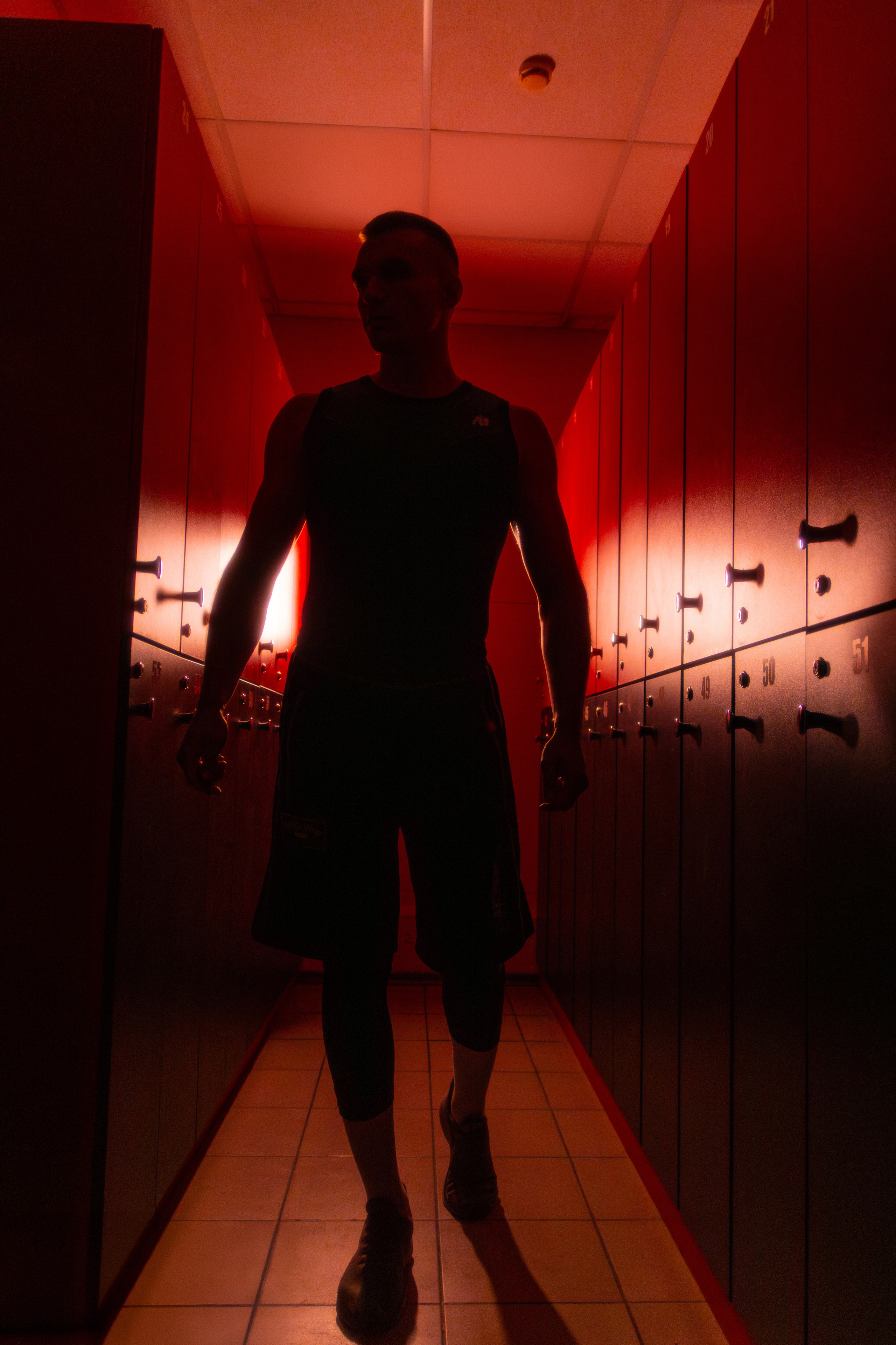 Эффектная фотография мускулистого тренера на фоне неоновых огней, демонстрирующая мощь и грацию спортивного тела.