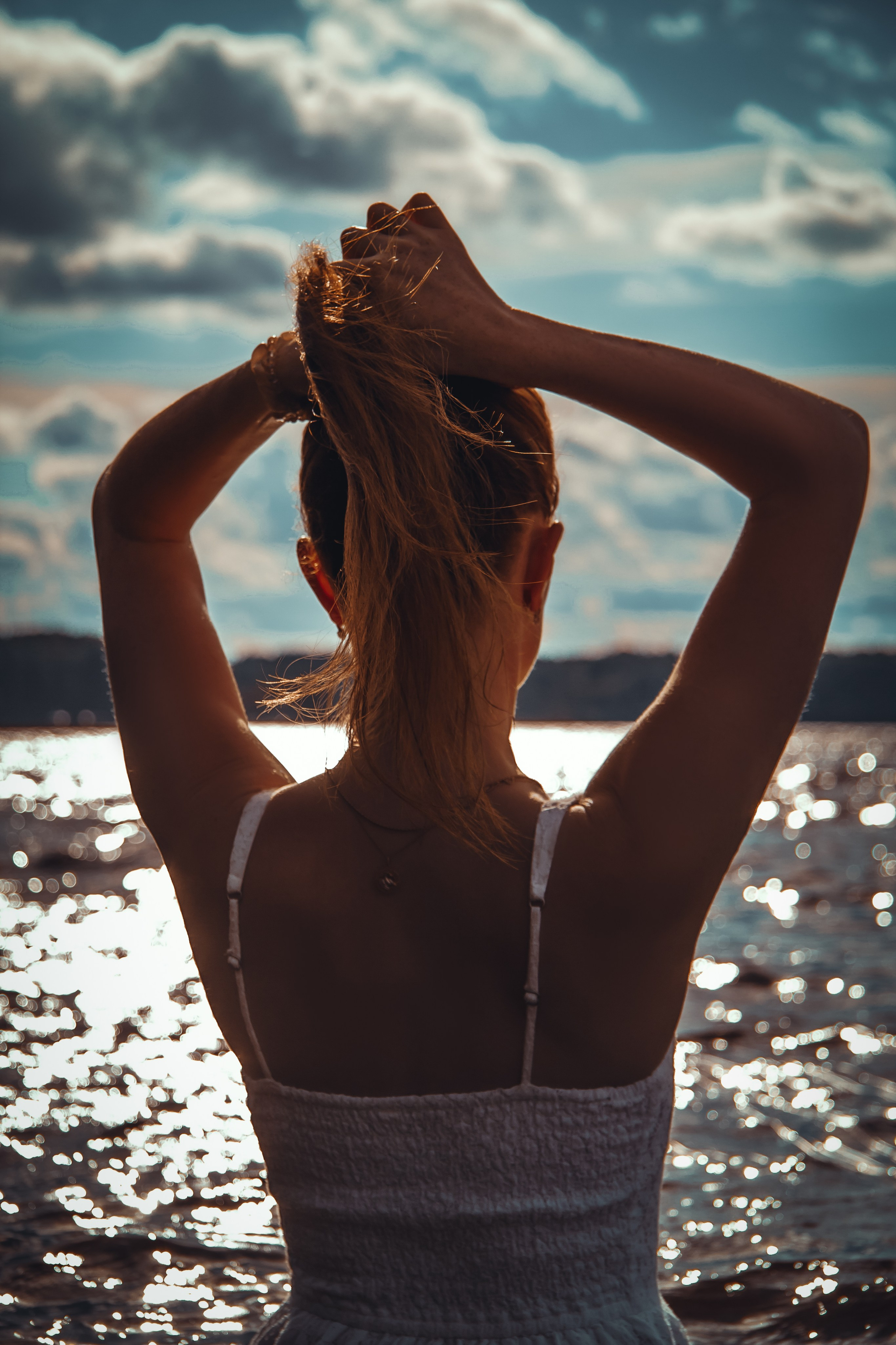 Закатные лучи солнца на берегу озера красивая девушка.