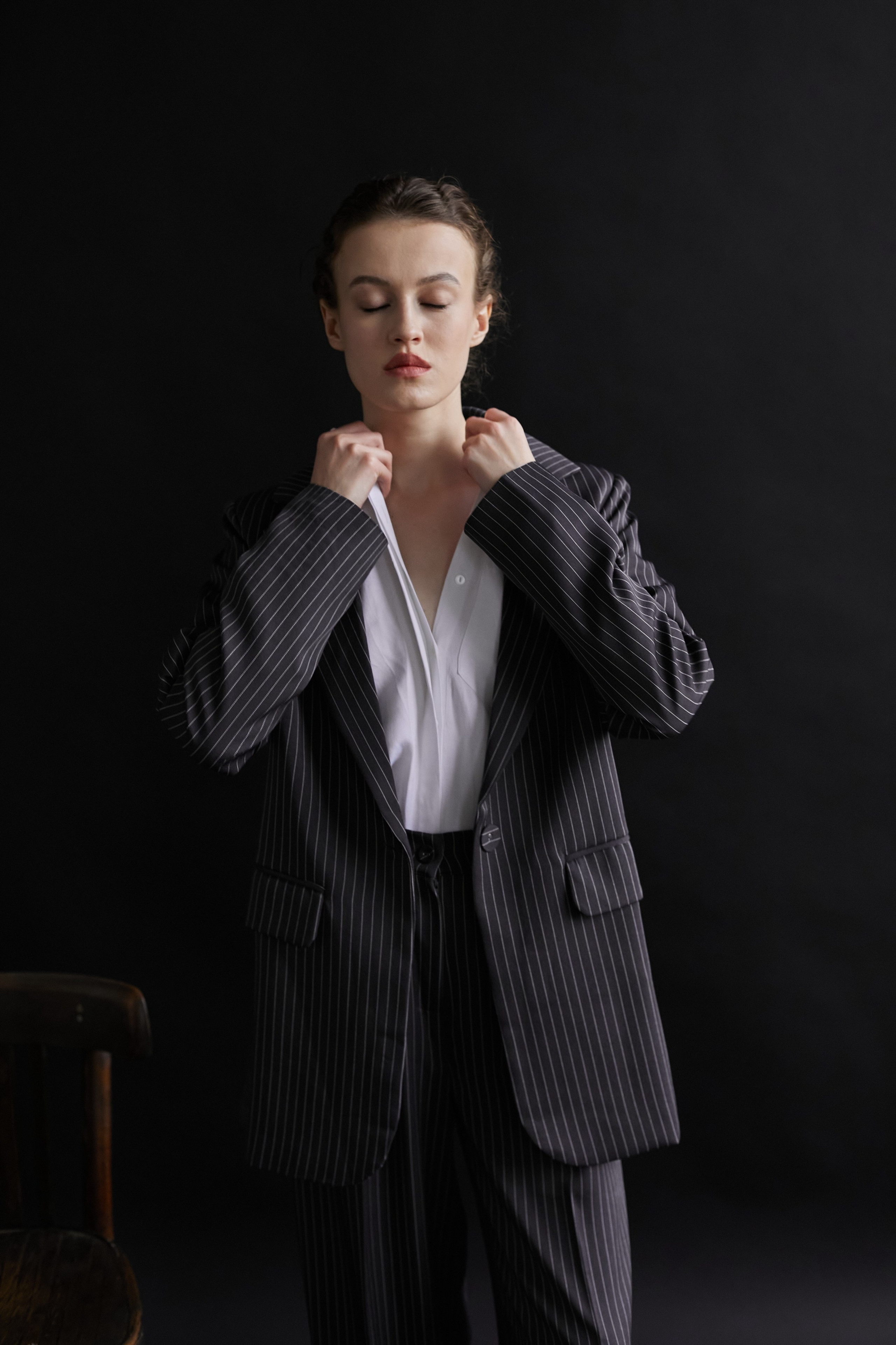 Фотограф в Москве. Студия. Студийный портрет. Девушка в пиджаке. Девушка на стуле на черном фоне. Красивая девушка в мужском костюме. Женский портрет.