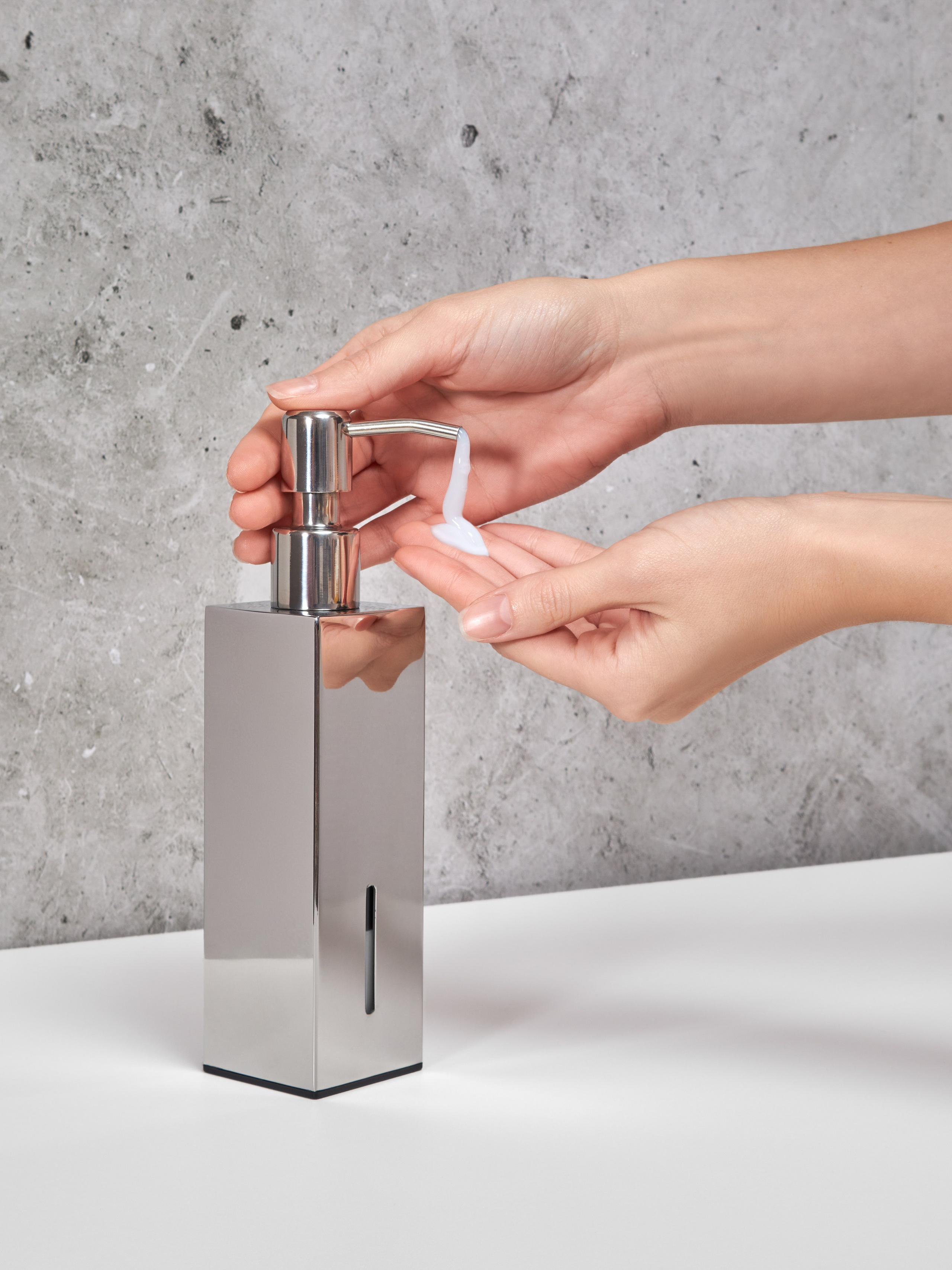 Предметная фотосъёмка металлического дозатора для мыла с руками модели в кадре в интерьере ванной комнаты